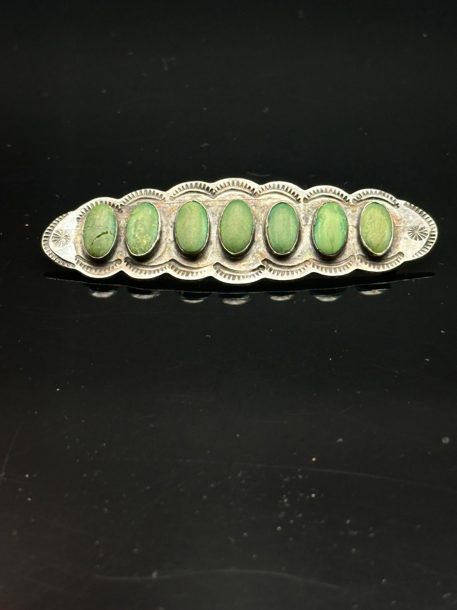 Vintage Navajo Sterling Silver & Green Turquoise Row Brooch: Beautiful vintage Navajo sterling silver brooch featuring seven oval green turquoise cabochons set in hand-tooled bezels. The scalloped edge is accented with traditional Navajo stamp work. Stamped “