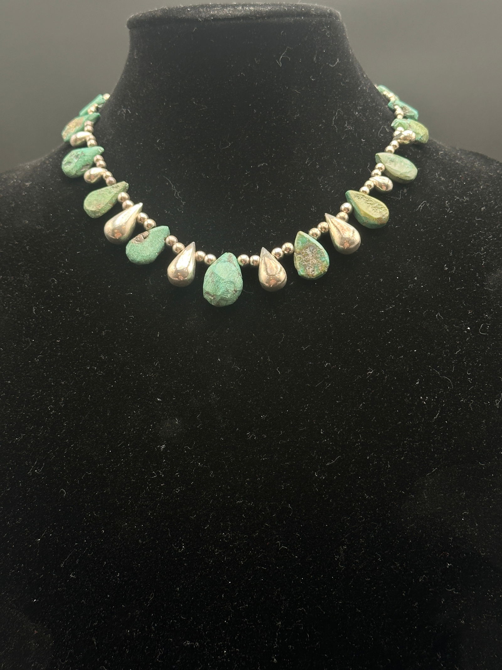 Vintage Navajo Turquoise & Sterling Silver Raindrop Necklace: This striking vintage Navajo-style necklace features alternating natural turquoise nuggets and sterling silver raindrop-shaped drops, strung on sterling beads. The piece displays an earthy green-blue
