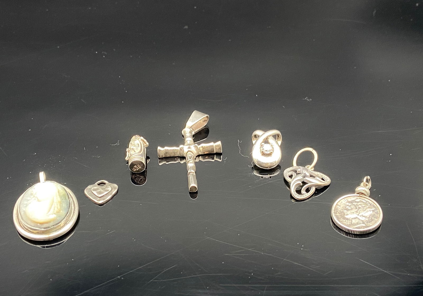 Collection of Seven Sterling Silver Pendants – Religious, Coin & Artisan Designs: A varied and collectible group of seven sterling silver pendants, including religious, novelty, and artistic designs:1.Round Cameo Pendant – Raised carved profile in mother-of-pearl or shell, bezel