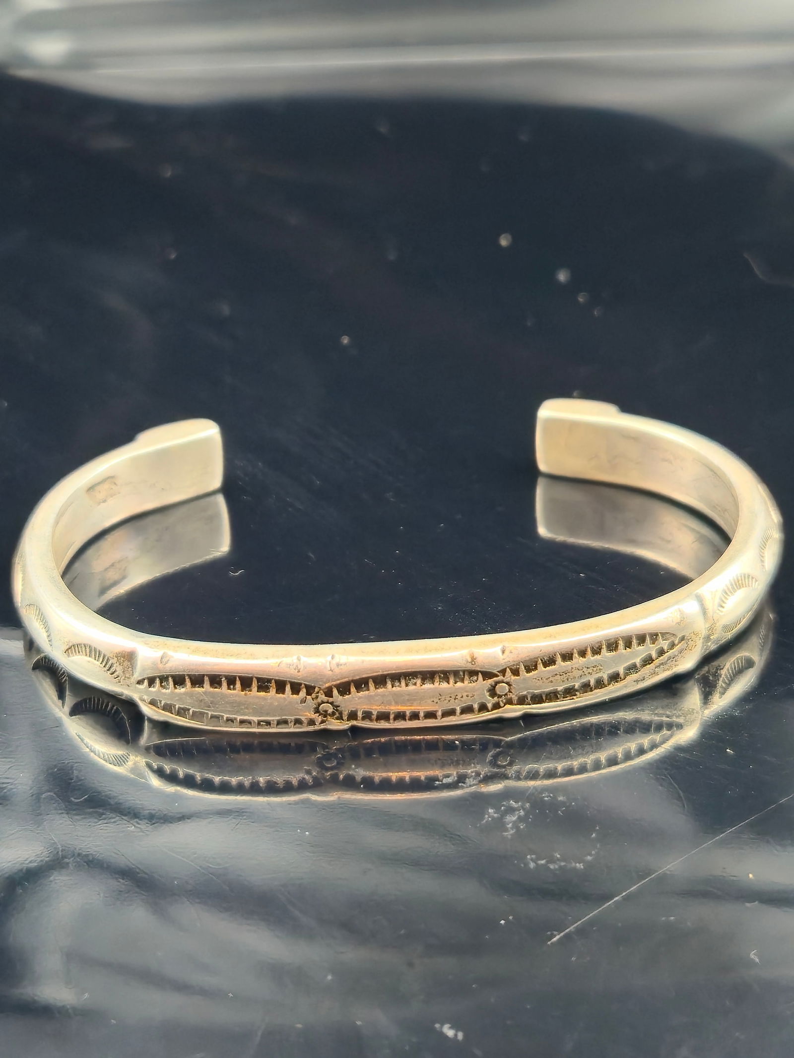 Vintage Sterling Silver Hand-Stamped Southwestern/Mexican Cuff, 38.5g: A vintage sterling silver cuff bracelet, mid-20th century, featuring hand-stamped geometric and oval sunburst designs along the band. Ends finished with concentric stamped motifs. Style is consistent