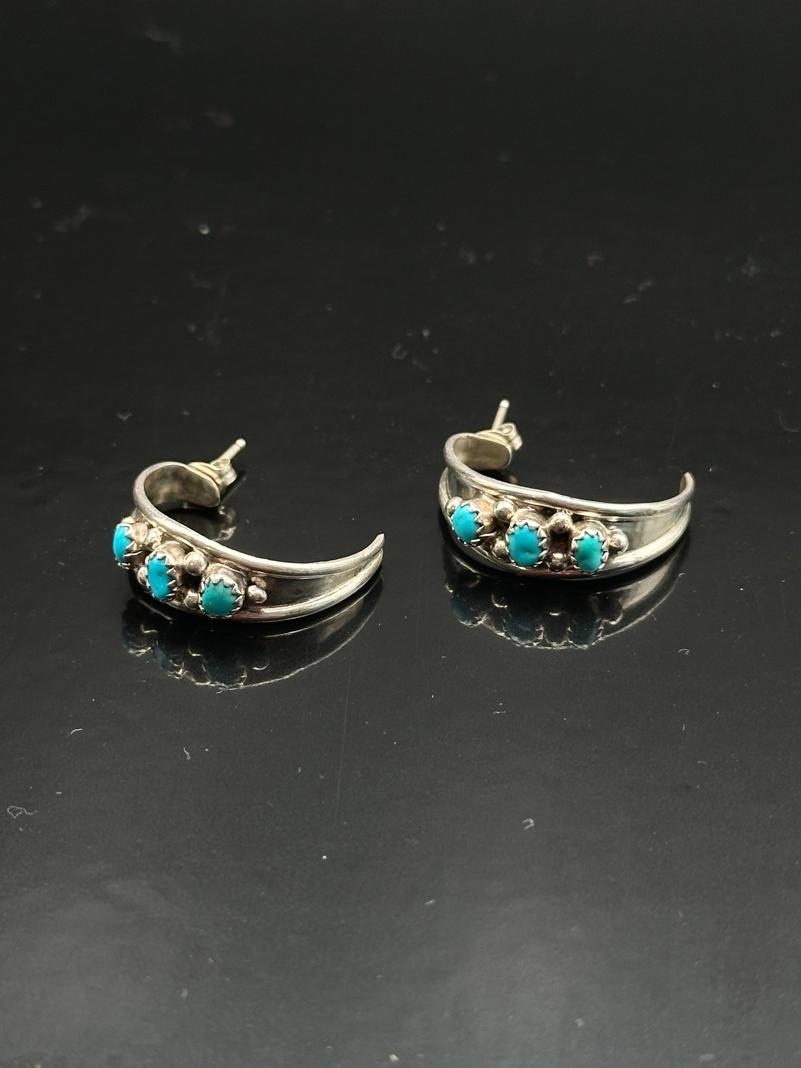 Ella Cowboy Navajo Sterling Silver Turquoise Hoop Earrings: Handcrafted by Navajo silversmith Ella Cowboy, these vintage sterling silver hoop earrings feature three vibrant turquoise cabochons on each earring, accented by silver beadwork. The graceful curved d