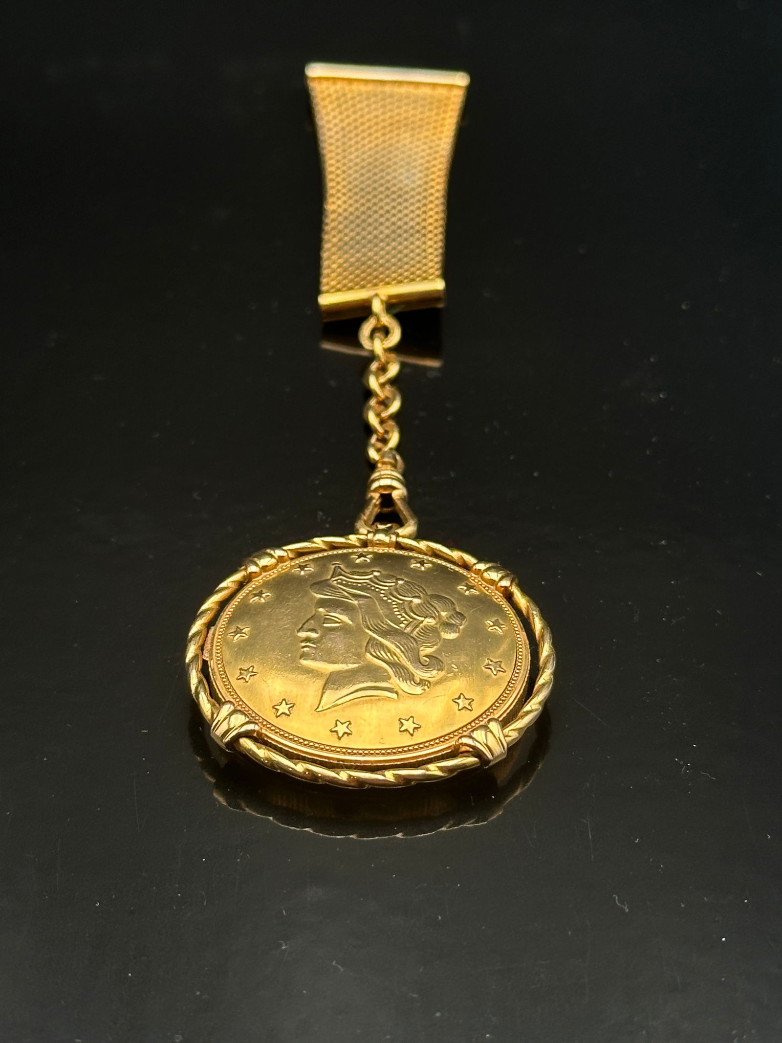 Vintage Gold-Tone Liberty Head Coin Fob / Money Clip: A vintage gold-tone fob featuring a Liberty Head coin design with stars around the border, suspended from a textured clip by a short chain. The coin is mounted in a twisted rope bezel frame, adding a