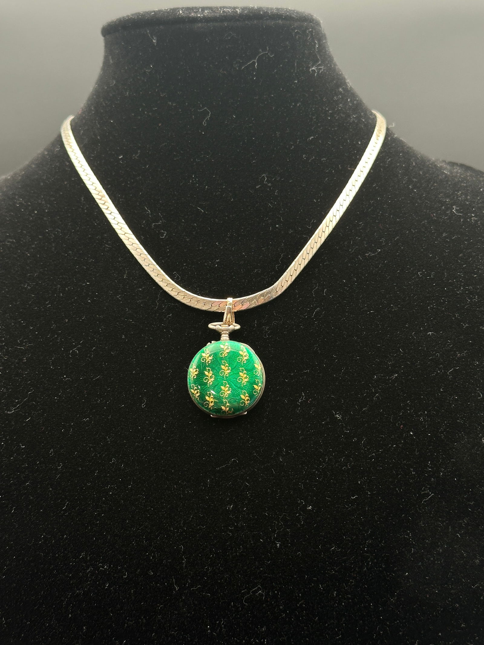 Vintage Swiss Green Enamel Pocket Watch Pendant on Italian Sterling Silver Chain: A beautiful vintage Swiss pocket watch, creatively repurposed as a pendant. The watch case is adorned with vivid green guilloché enamel, decorated with repeating gilt floral motifs. The back of the c