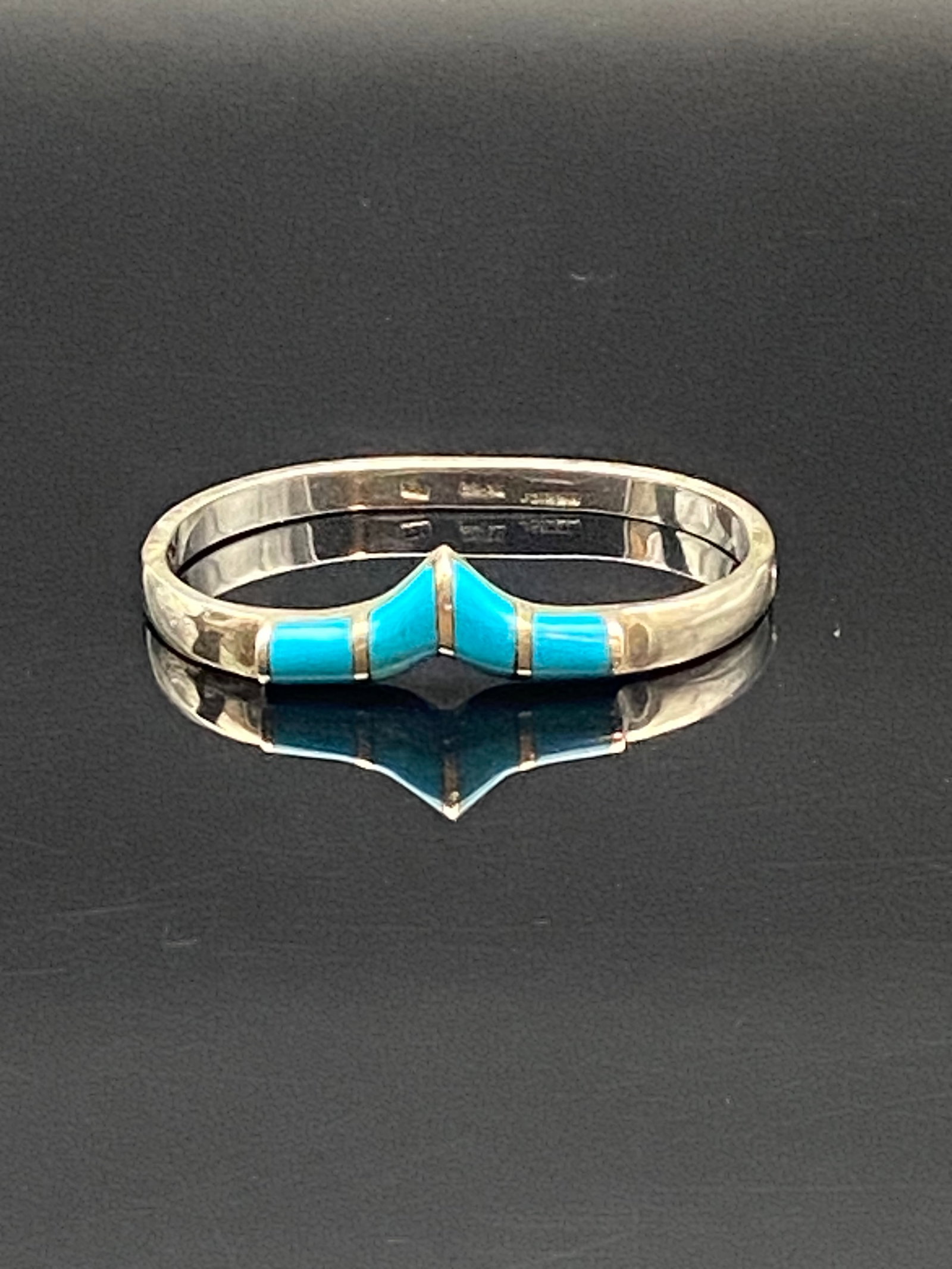 Mexican Sterling Silver Turquoise Inlay Chevron Bracelet (Taxco): A sleek handcrafted sterling silver bracelet featuring a bold chevron design set with vibrant turquoise inlay. The minimalist yet striking geometric form highlights the vivid blue of the turquoise aga