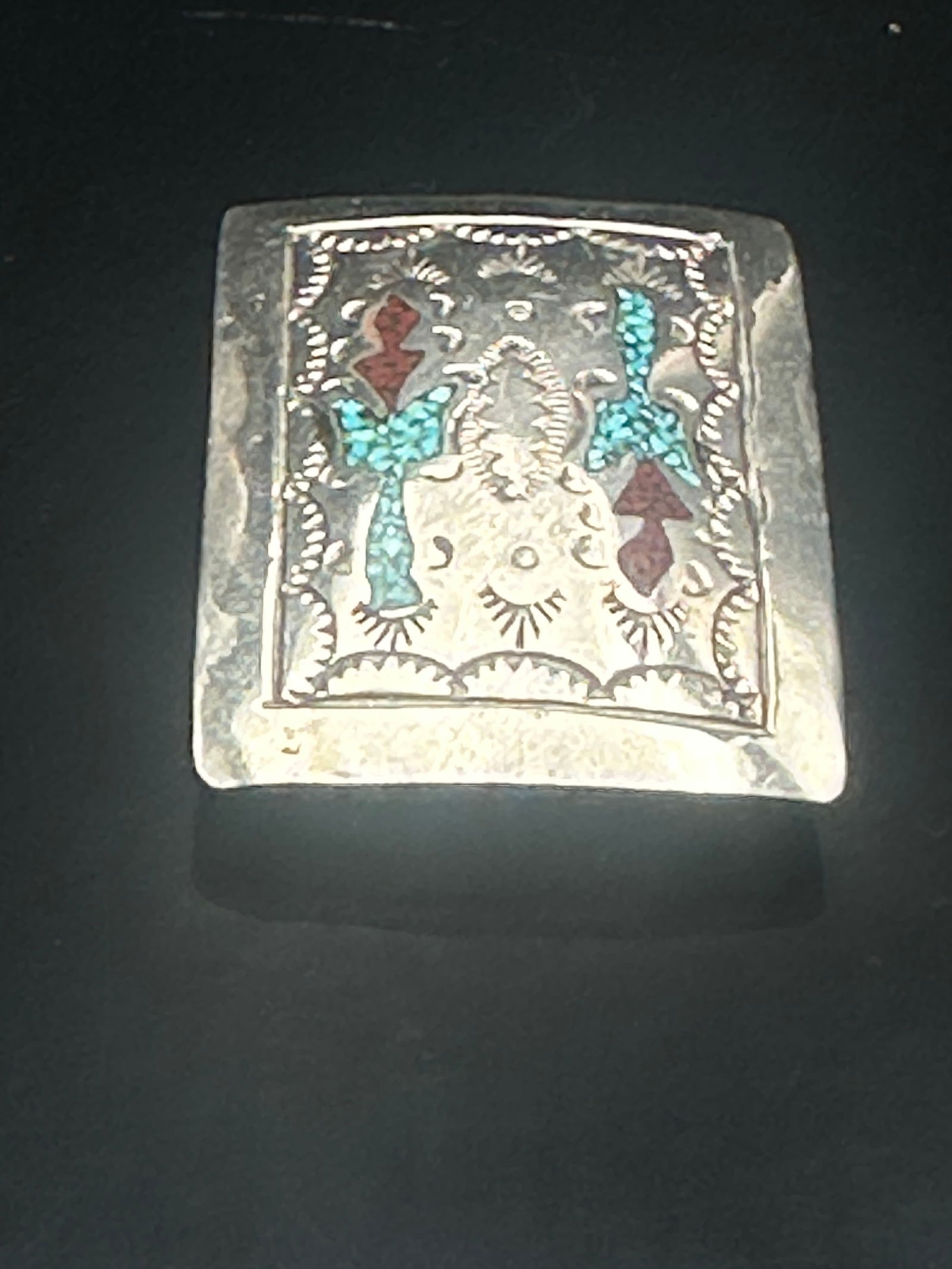 Vintage Handcrafted Silver Belt Buckle with Turquoise & Coral Inlay: A striking vintage silver belt buckle featuring intricate hand-tooled designs and vibrant stone inlay. The buckle is decorated with turquoise and red coral inlay in a traditional arrow motif, surround