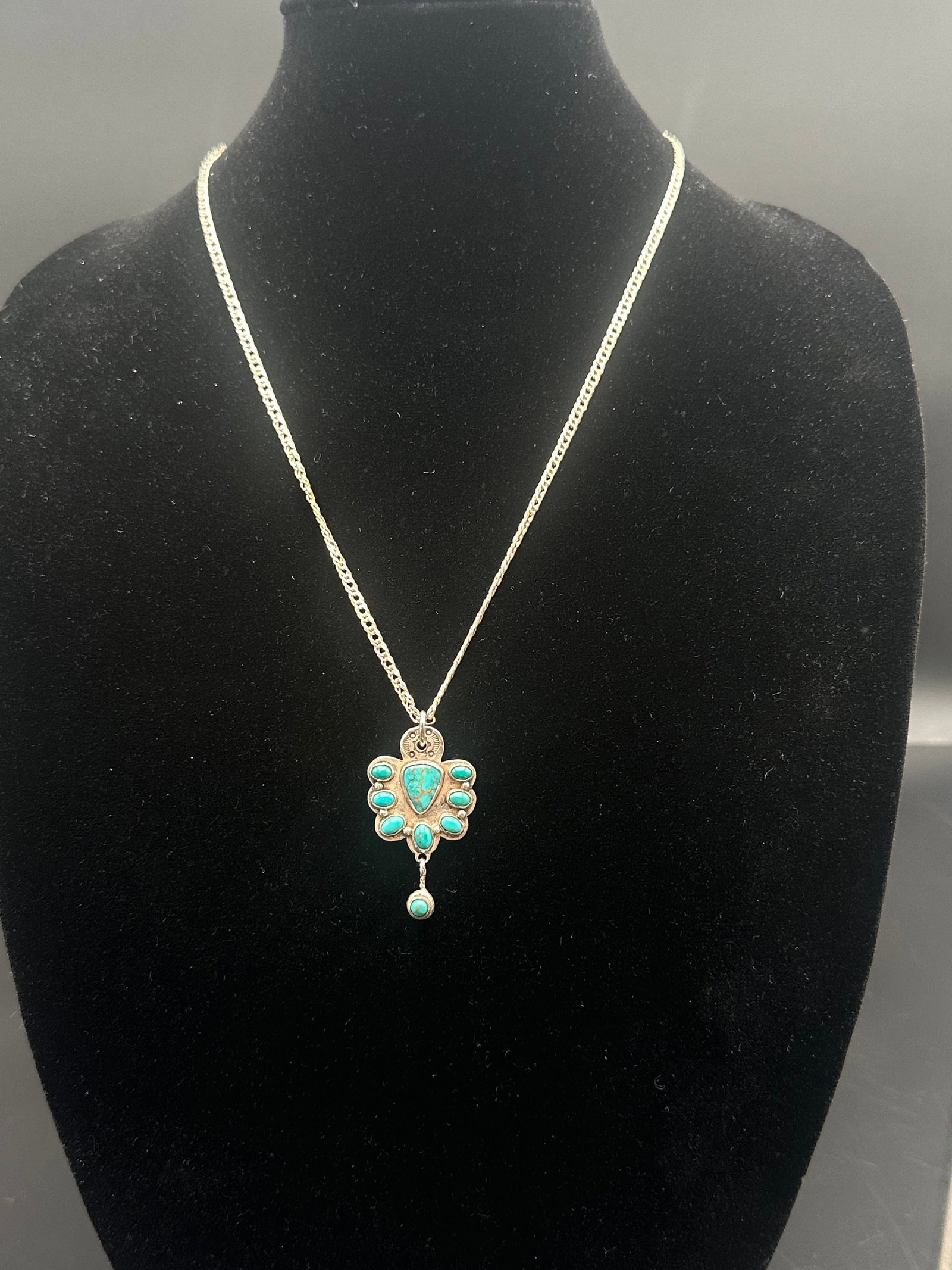 Sterling Silver Necklace w/ Turquoise Cluster Pendant: Sterling silver chain with an ornate turquoise cluster pendant. The pendant showcases a central triangular turquoise stone surrounded by smaller turquoise cabochons and a suspended turquoise drop. Sta