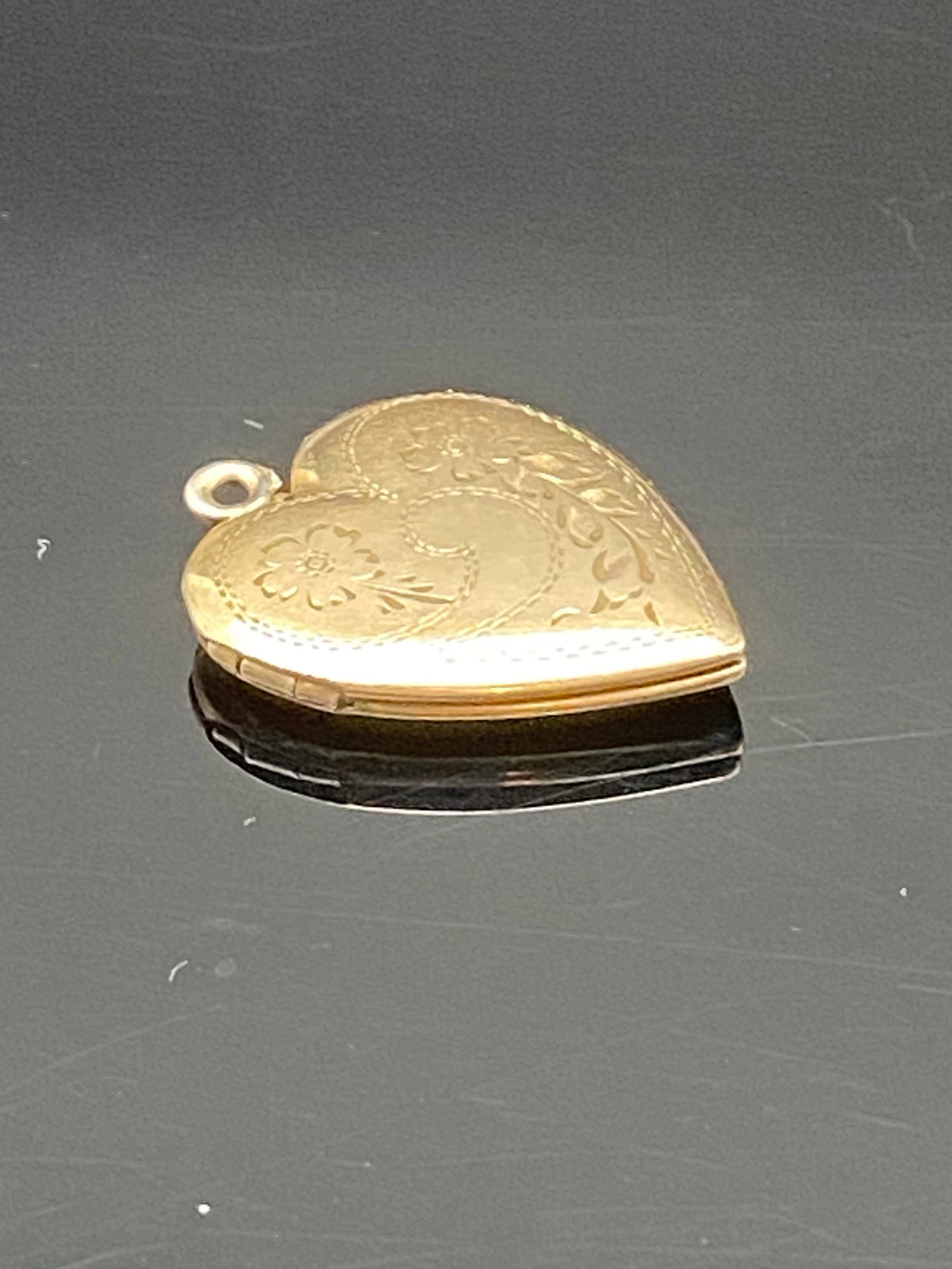 Vintage Gold-Tone Heart Locket Pendant: Charming vintage gold-tone heart-shaped locket with intricate floral and scroll engraving on the front. The hinged design opens to reveal two heart-shaped compartments for small photos or keepsakes. S