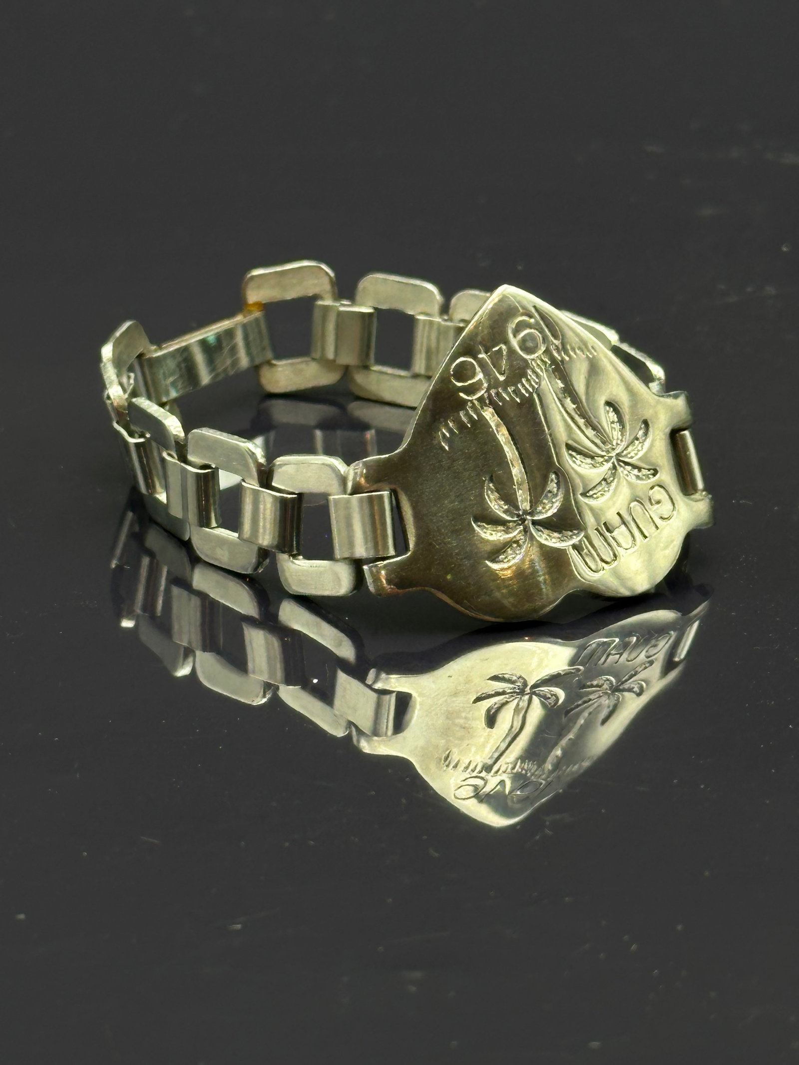Vintage 1946 Guam Souvenir Bracelet with Palm Tree Motif: Vintage souvenir bracelet featuring rectangular links and a central shield-shaped plaque engraved “GUAM 1946” with palm tree designs. Likely produced as a post-WWII memento for servicemen or t