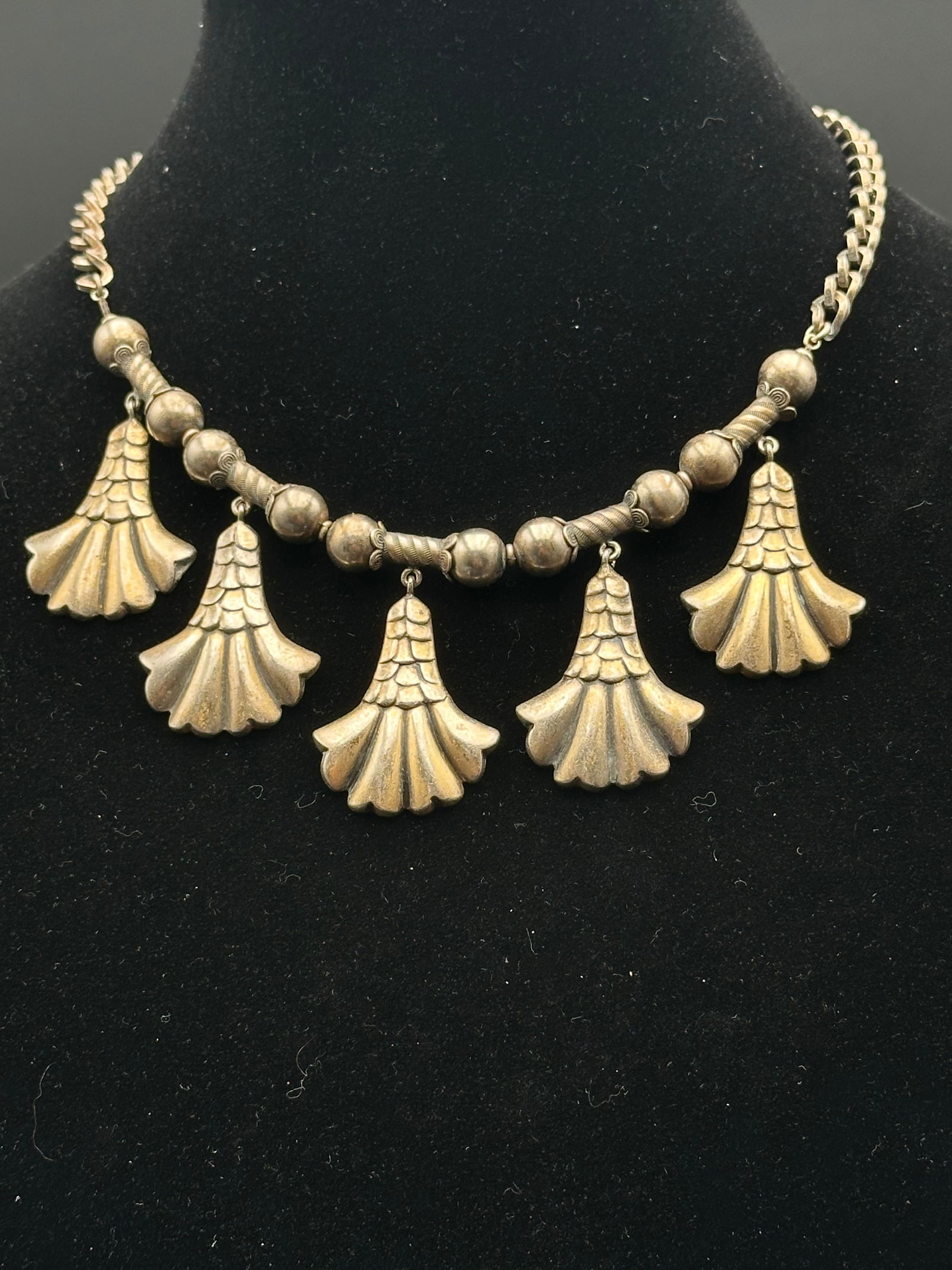 Joseff of Hollywood Gilt Necklace with Scalloped Drop Pendants: A vintage Joseff of Hollywood necklace featuring five scalloped, fan-shaped drop pendants suspended from a chain of textured beads and links. The piece is crafted in the brand’s signature Russian go