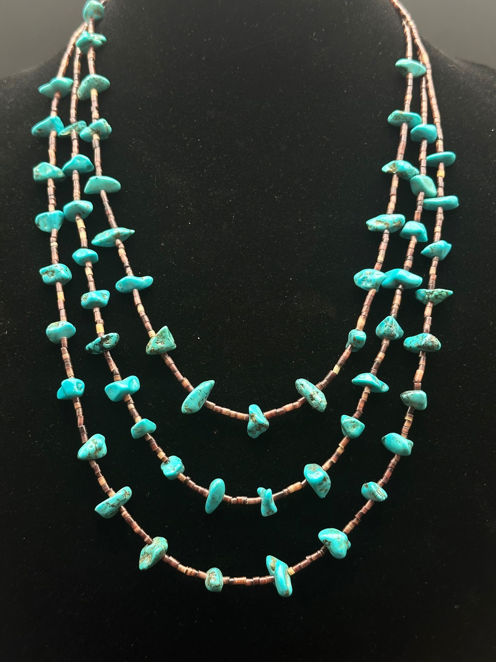 Vintage Three-Strand Turquoise Nugget & Heishi Bead Necklace – 29g: Beautiful vintage three-strand necklace featuring natural turquoise nuggets with rich matrix patterns, strung alongside traditional brown heishi beads. The combination creates a striking Southwestern