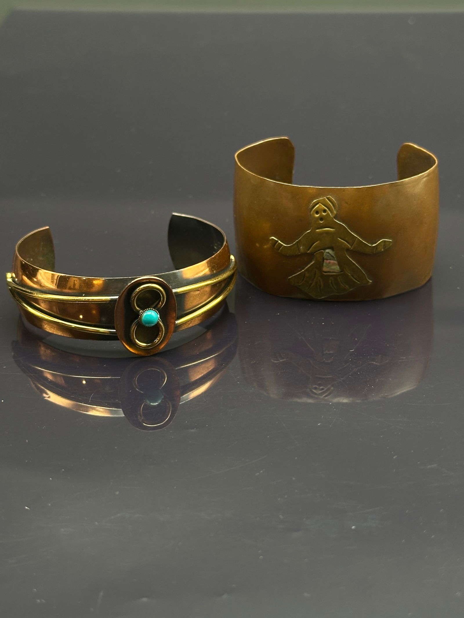 Pair of Vintage Genuine Copper Cuff Bracelets – Figural & Turquoise Accent: Lot of two vintage genuine copper cuff bracelets:•Figural cuff: Features a stylized dancer/kachina motif with abalone shell inlay detail.•Modernist cuff: Wide copper design accented with a t