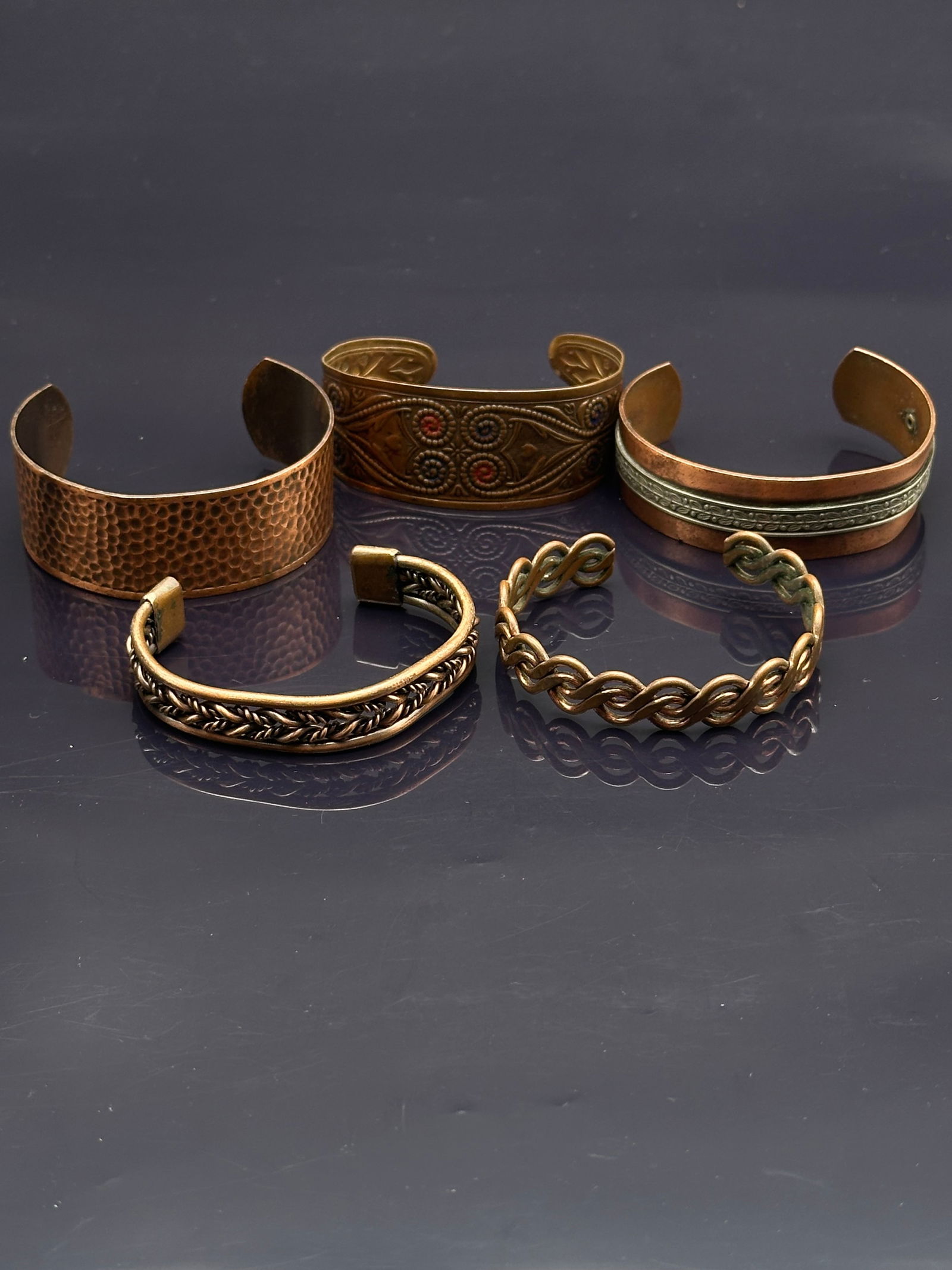 Lot of 5 Vintage Copper Cuff Bracelets – Hammered, Braided, and Decorative Designs: Collection of five vintage copper cuff bracelets, each with unique design details:•Hammered copper cuff with a bold hand-wrought texture•Decorated cuff with circular stamped motifs and red e