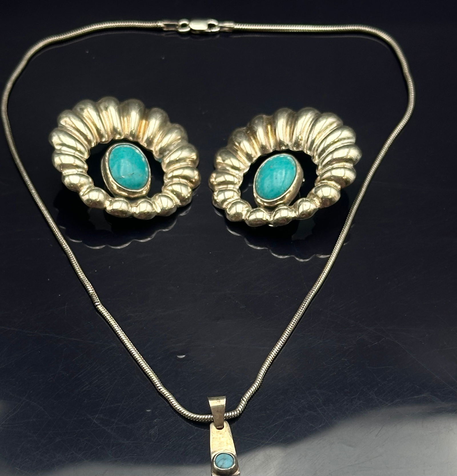 Mexican Sterling Silver Turquoise Earrings & Pendant Necklace Set – 30.7g: Vintage Mexican sterling silver jewelry set including a pair of bold clip-on earrings with scalloped frames and turquoise cabochons, paired with a sterling silver chain necklace featuring a modern tur