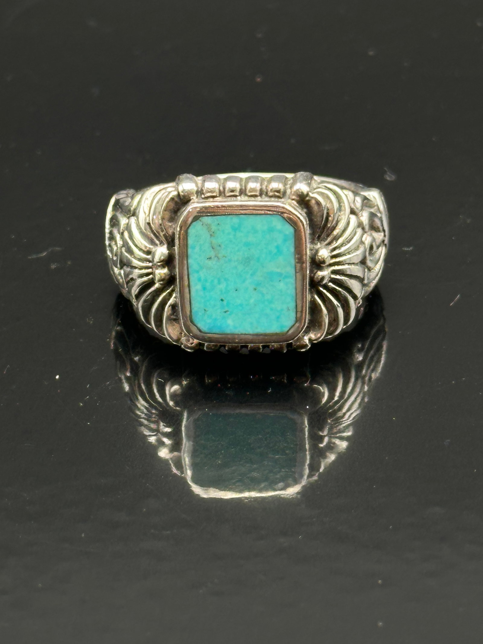Sterling Silver Ornate Turquoise Ring, Marked 925: Sterling silver ring featuring a rectangular turquoise cabochon set in a bezel with scalloped edges. Ornate shoulders with beadwork and scroll details. Marked 925 inside band. Likely Southwestern-insp