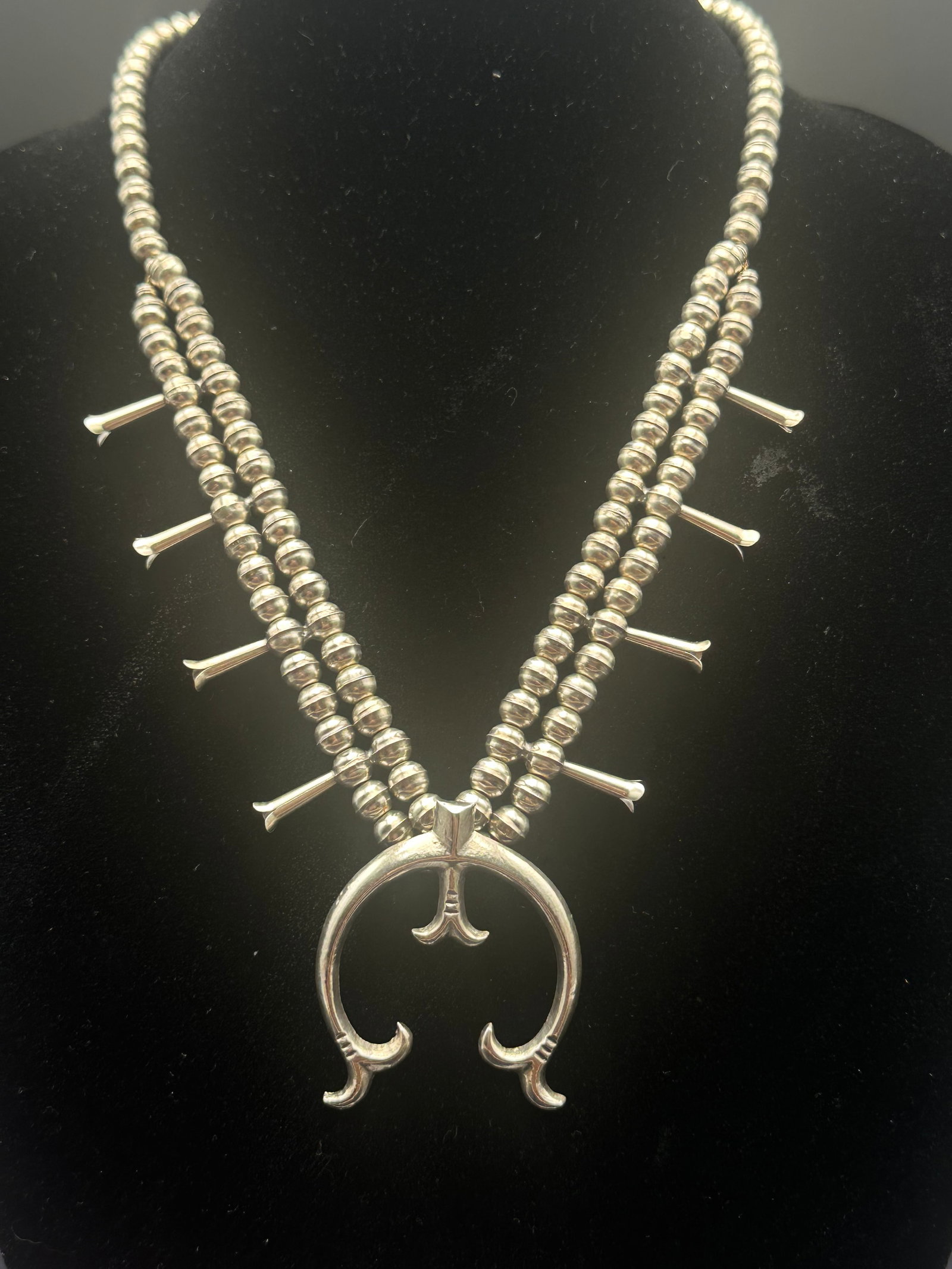 Navajo Sterling Squash Blossom Necklace Signed P. Begay, 65g: Authentic Navajo squash blossom necklace crafted in sterling silver. Features double strands of hand-made silver beads, flared squash blossoms, and a bold naja pendant. Reverse marked Sterling and sig