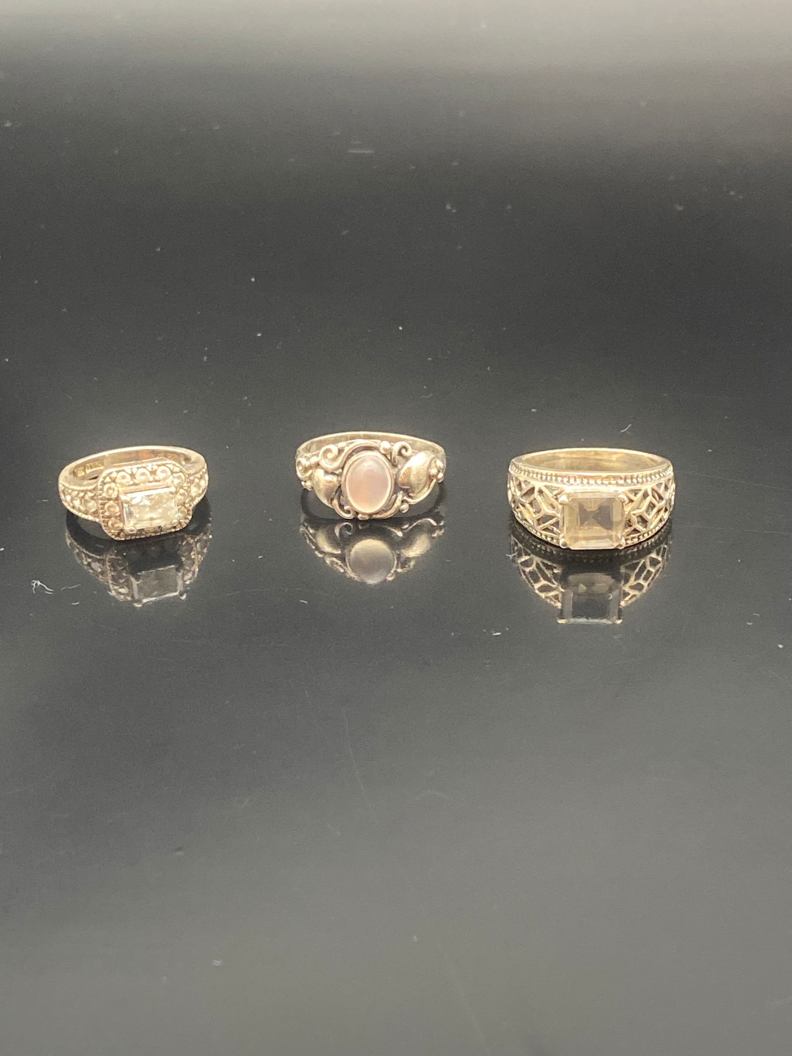 Trio of Vintage Sterling & Gold-Tone Rings – Gemstone & Filigree Designs: A charming set of three vintage-inspired rings featuring classic gemstone and filigree details:•Left: Square-cut clear stone framed by marcasite-style accents in a detailed gold-tone band.•C