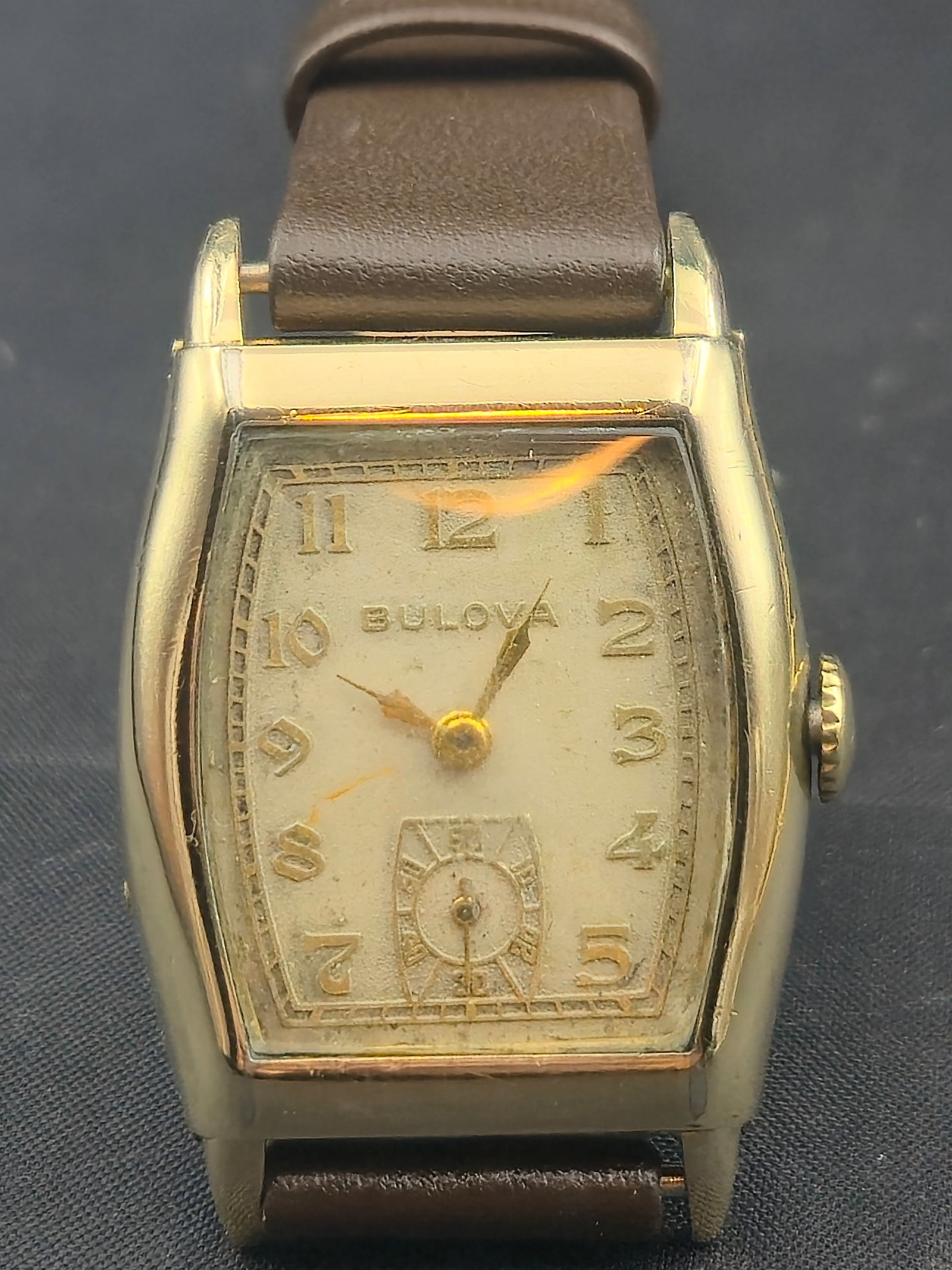 1934 Bulova 10K RGP 25mm Tonneau Wristwatch w/ 10AN 15J Movement – Running: Early 1934 Bulova men’s wristwatch in a classic tonneau case design, crafted with a 10K rolled gold plate bezel and stainless steel back. Caseback is engraved “Verneth White, 5-31-34,” givin