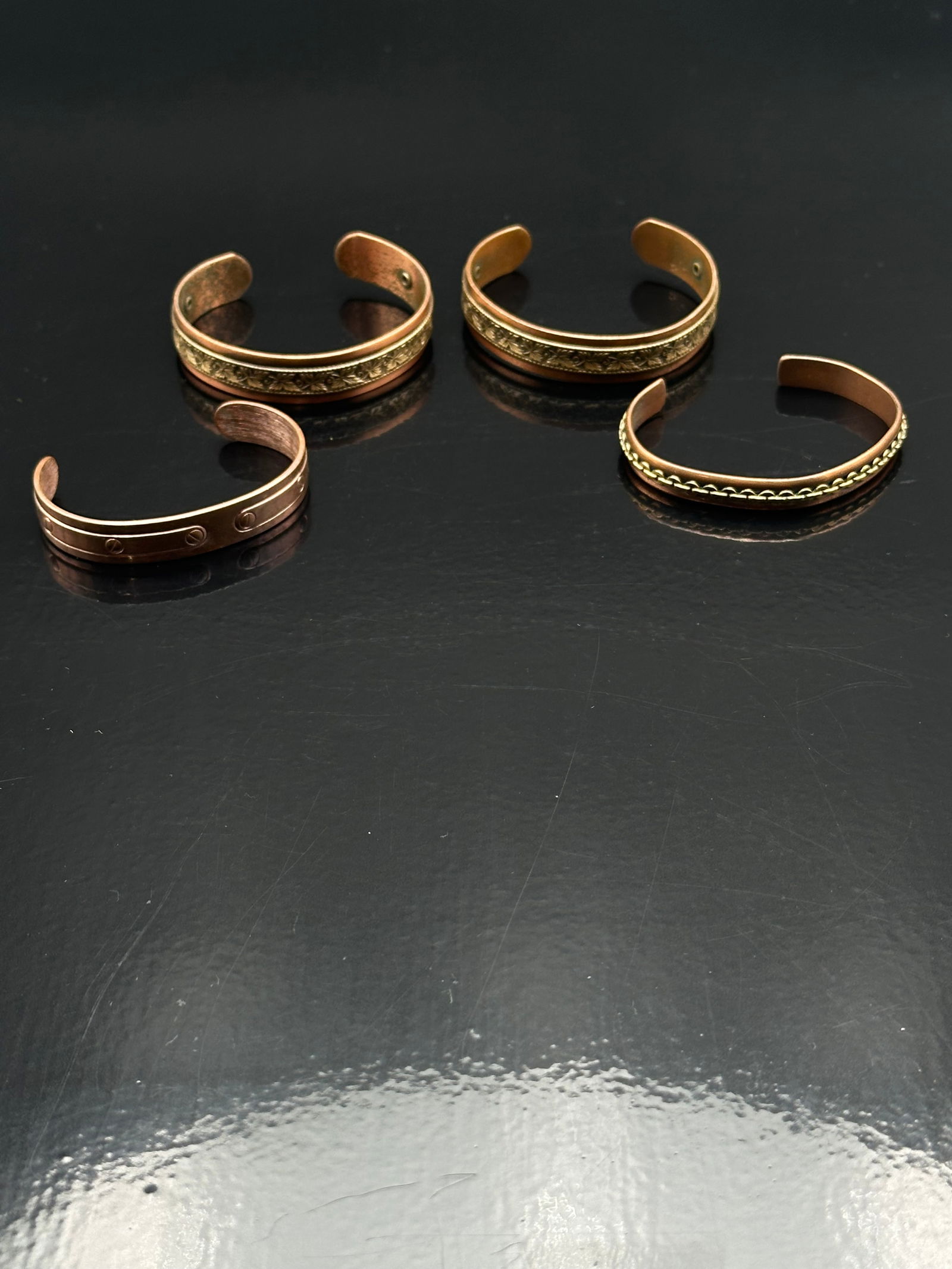 Set of 4 Vintage Copper Cuff Bracelets with Brass Accents – 76g: Offered here is a collection of four vintage copper cuff bracelets, each featuring unique designs and brass detailing. Two cuffs display repeating diamond-pattern brass inlays, one has a rope-style br