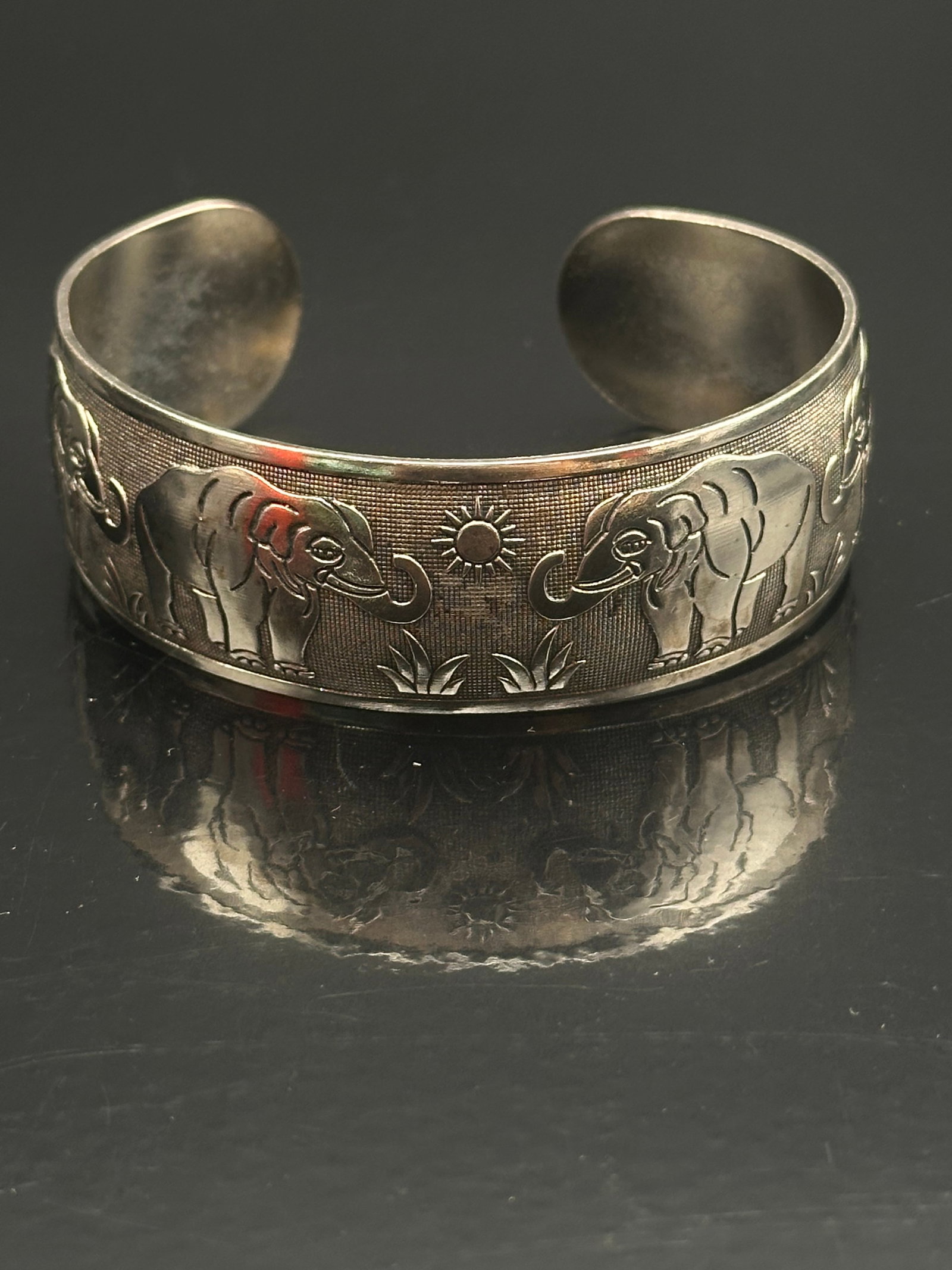 Vintage Sterling Silver Elephant Motif Cuff Bracelet – 36.1g: A charming vintage sterling silver cuff bracelet featuring a continuous engraved design of elephants in relief. The elephants are depicted in a walking procession across a textured background, giving