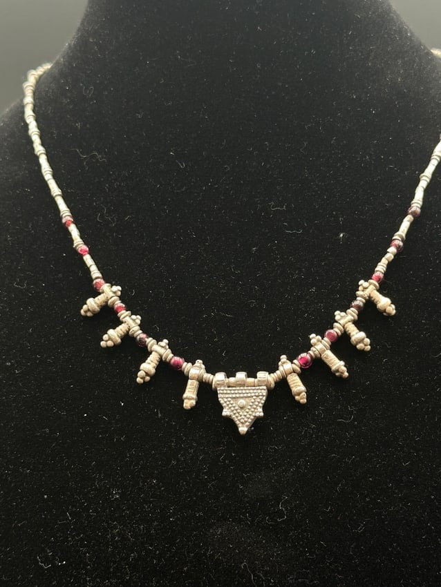 Tribal Sterling Silver Necklace with Red Bead Accents: Distinctive tribal-style sterling silver necklace featuring intricate beaded links, red accent beads, and dangling silver charms. The central pendant showcases detailed granulation work, adding textur