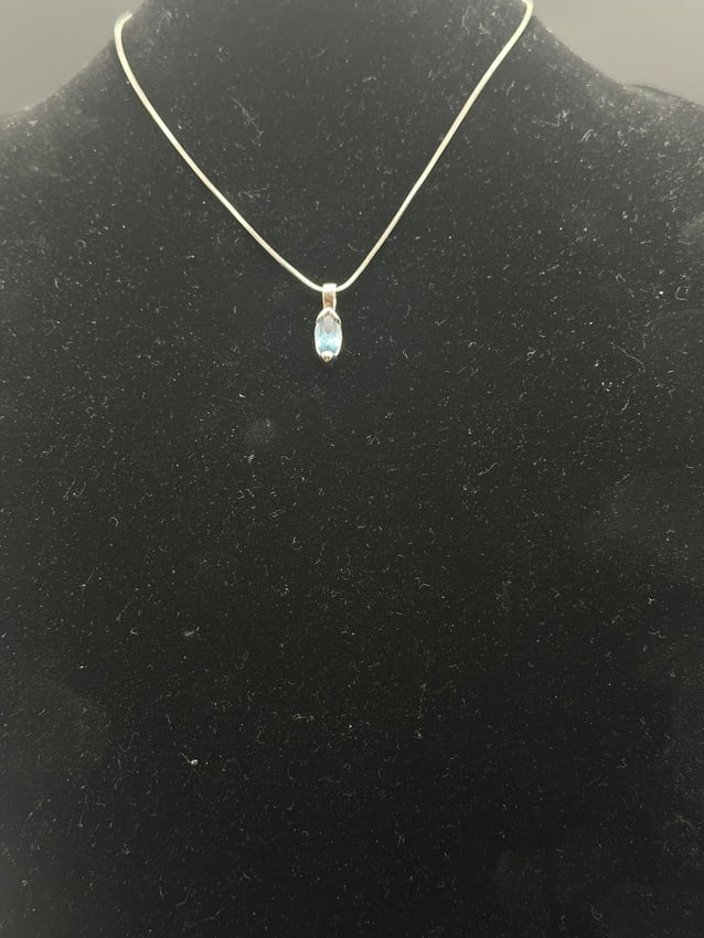 Sterling Silver Necklace with Marquise-Cut Blue Topaz Pendan: Elegant sterling silver necklace featuring a delicate chain with a marquise-cut blue topaz pendant. The faceted gemstone sparkles with a soft sky-blue hue, beautifully contrasted by the sleek silver s