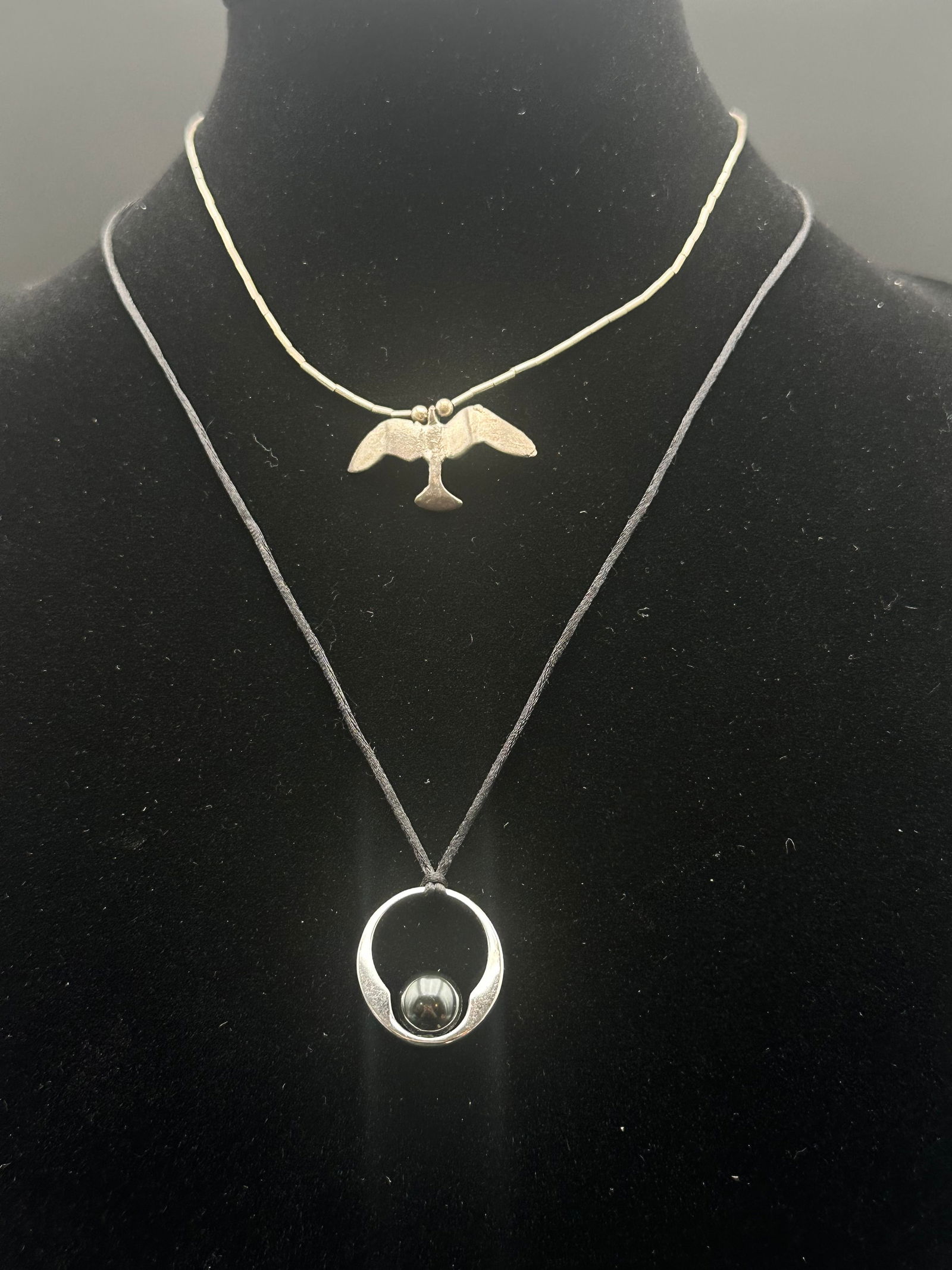 Lot of 2 Sterling Silver Necklaces – Thunderbird & Modern Hematite Orb Pendants: Two sterling silver necklaces featuring contrasting designs: a Thunderbird totem pendant on beaded silver strand representing strength and protection, and a modern circular pendant with hematite orb o