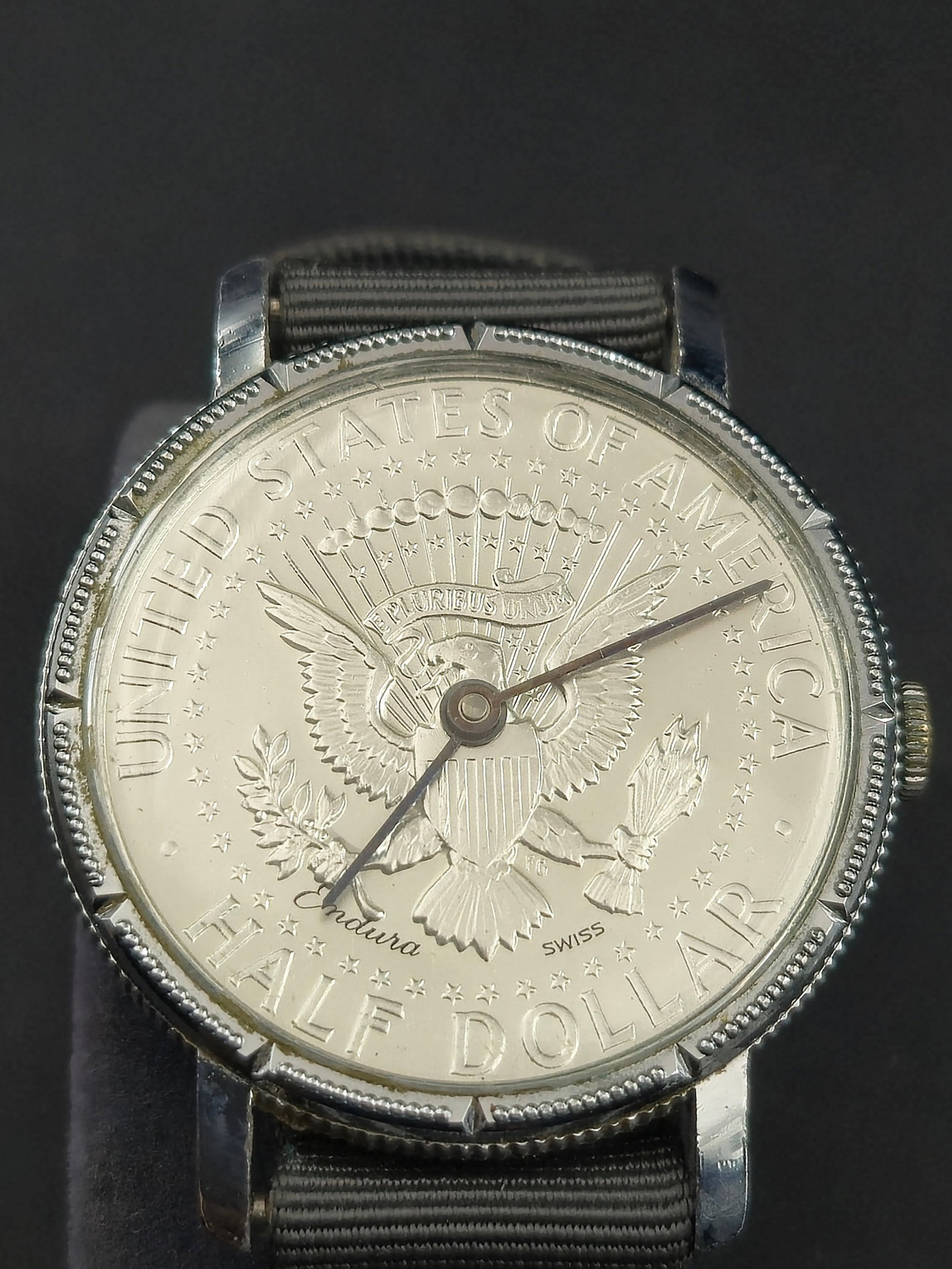 Swiss Endura Kennedy Half Dollar Coin Watch Mechanical Wristwatch – 35mm: This vintage Endura Coin Watch features a dial styled after the U.S. Kennedy Half Dollar, complete with the Presidential Seal and United States of America Half Dollar engraving. Swiss-made mechanical 
