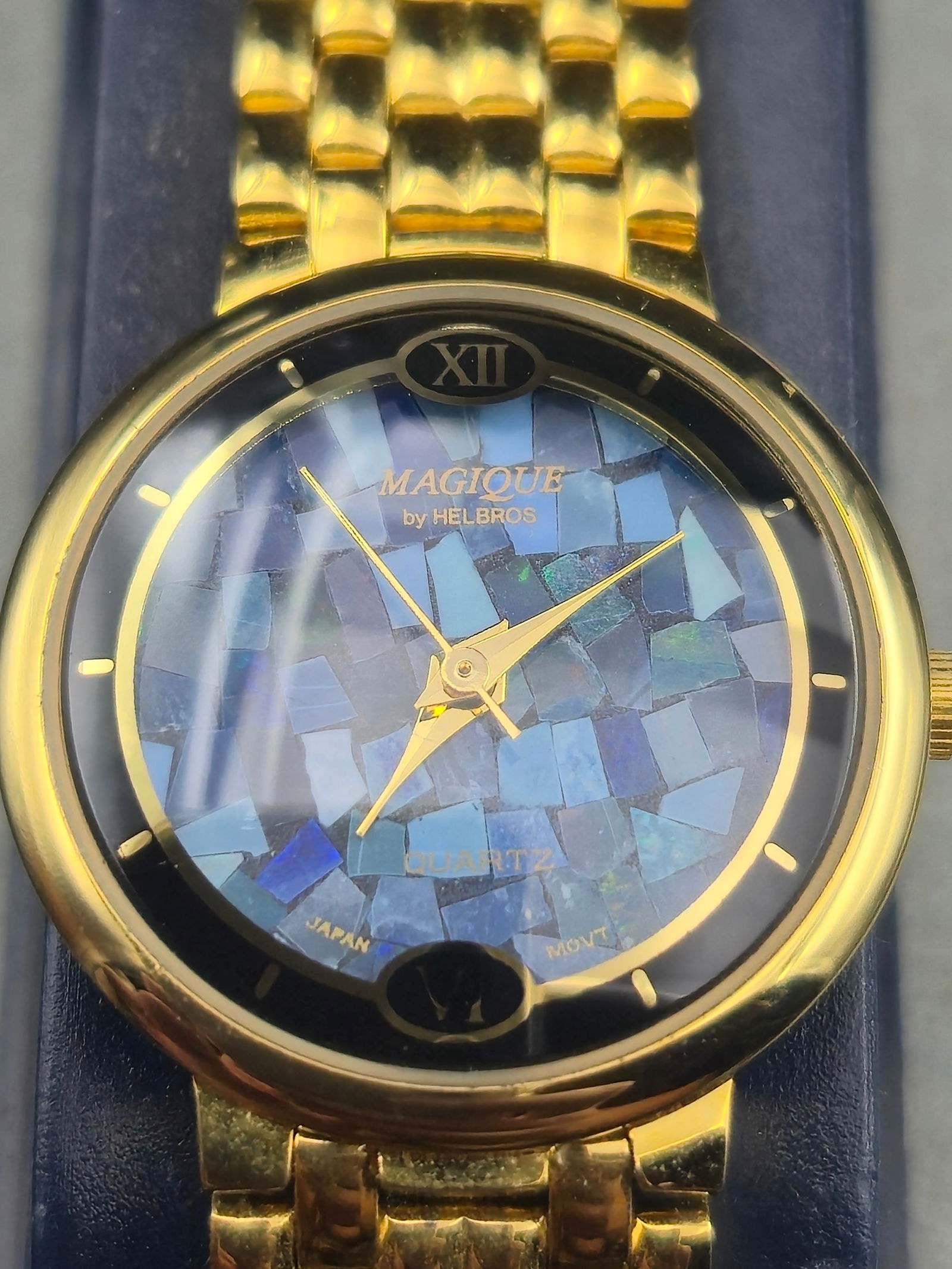 Ladies Magique by Helbros Quartz Watch Gold-Tone Bracelet Mosaic Dial w/ Box – Running: Offered is a ladies’ Magique by Helbros wristwatch, featuring a striking iridescent blue mosaic dial and slim gold-tone case. The watch is presented on its original gold-tone bracelet with polished