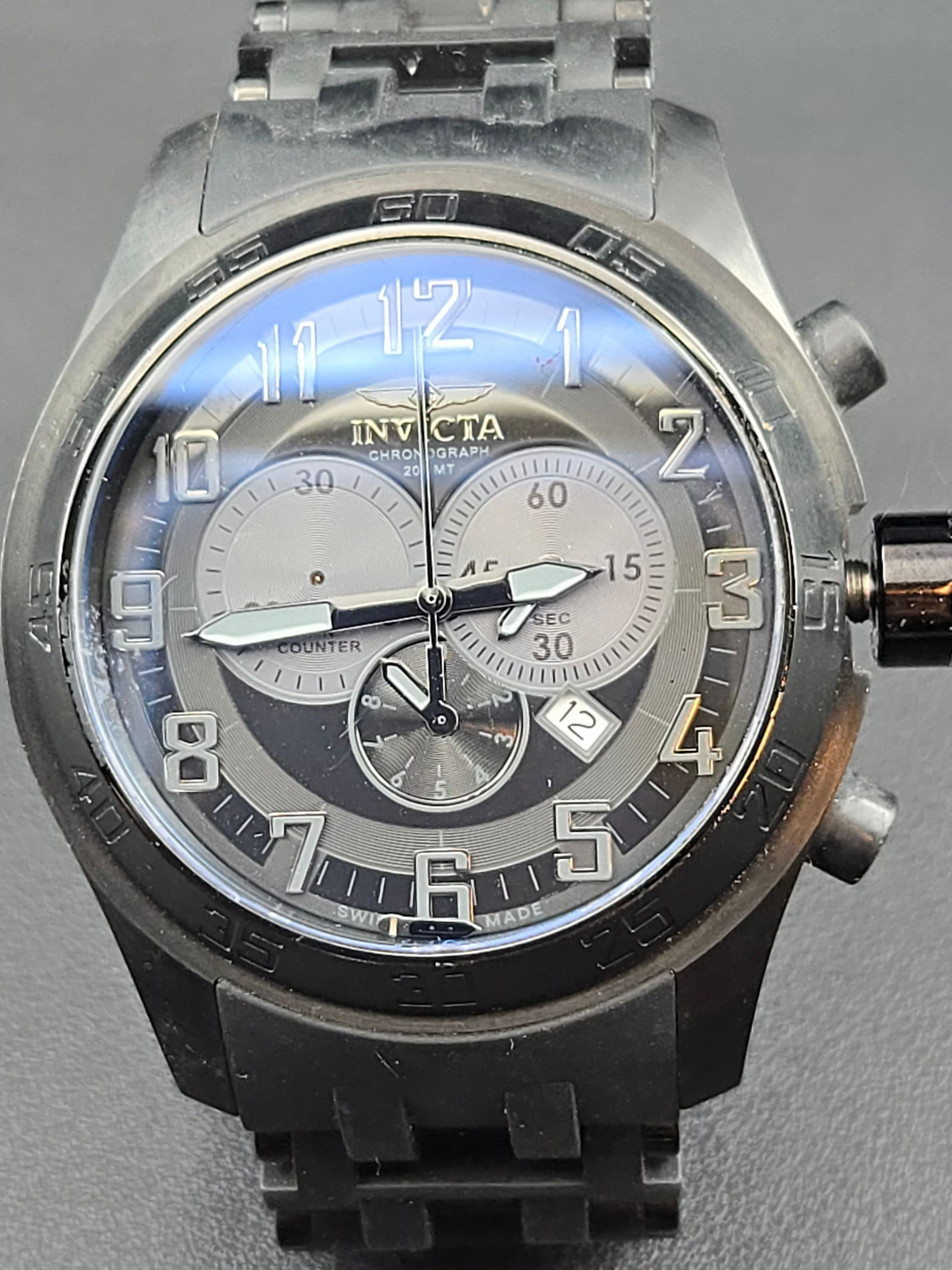 Invicta 5601 Swiss-Made Chronograph 50mm Black Steel Quartz Watch, Runs: Oversized Invicta Model 5601 chronograph wristwatch, measuring 50mm across, with a black PVD-coated stainless steel case and rotating bezel. Dial features grey/silver-tone finish with applied Arabic n