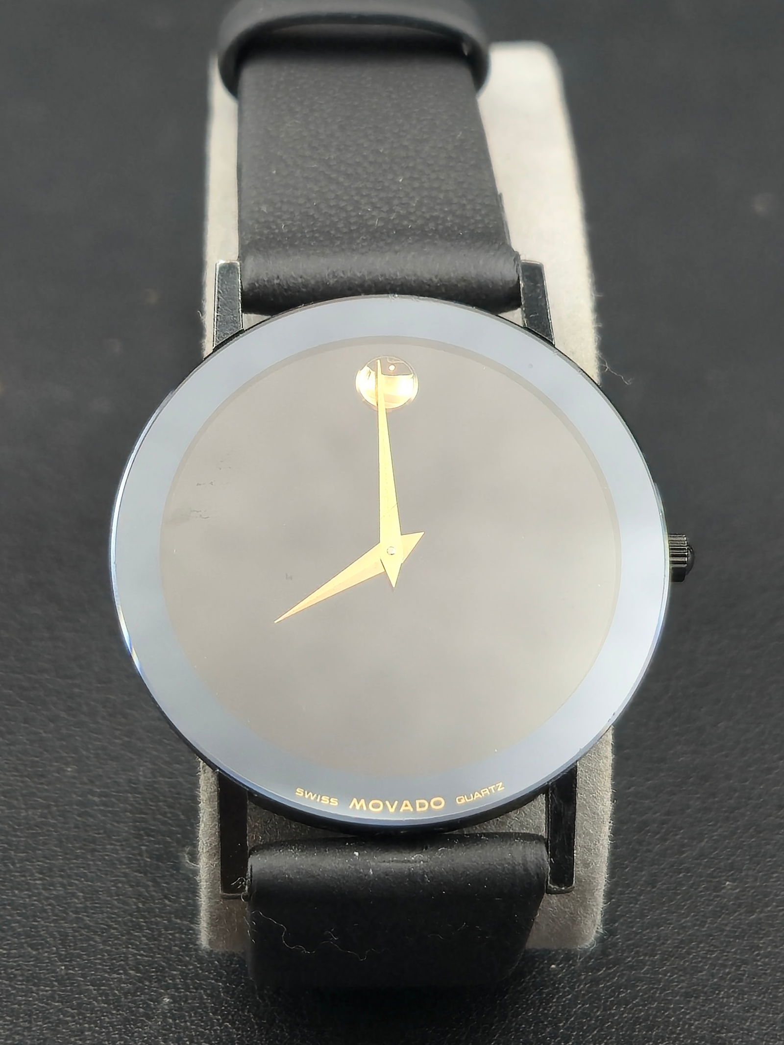 Movado Museum Classic 87-40-882N Black Dial 30mm Quartz Watch: Movado Museum Classic wristwatch featuring the brand’s signature minimalist black dial with a single gold dot at 12 o’clock, symbolizing the sun at high noon. The sleek 30mm black-toned case and g