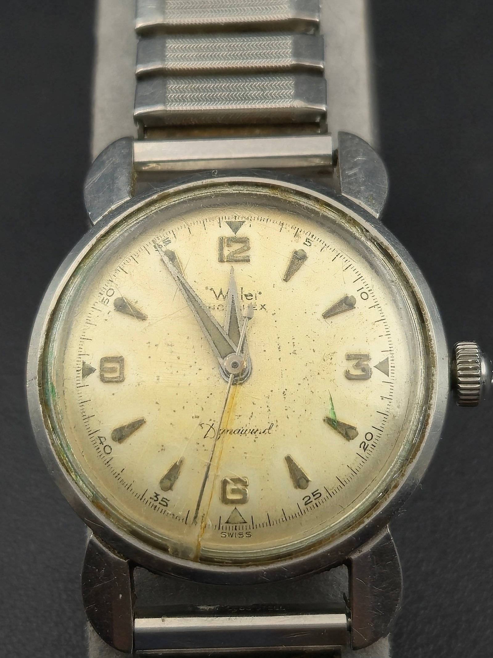 Wyler Dynawind Automatic E1256 Swiss 17J Stainless 35mm Men’s Watch – Running: Vintage Wyler Dynawind men’s automatic wristwatch featuring the Swiss Wyler Cal. E1256 17-jewel movement. The stainless steel “Brevet” case houses a cream patina dial with raised Arabic nume