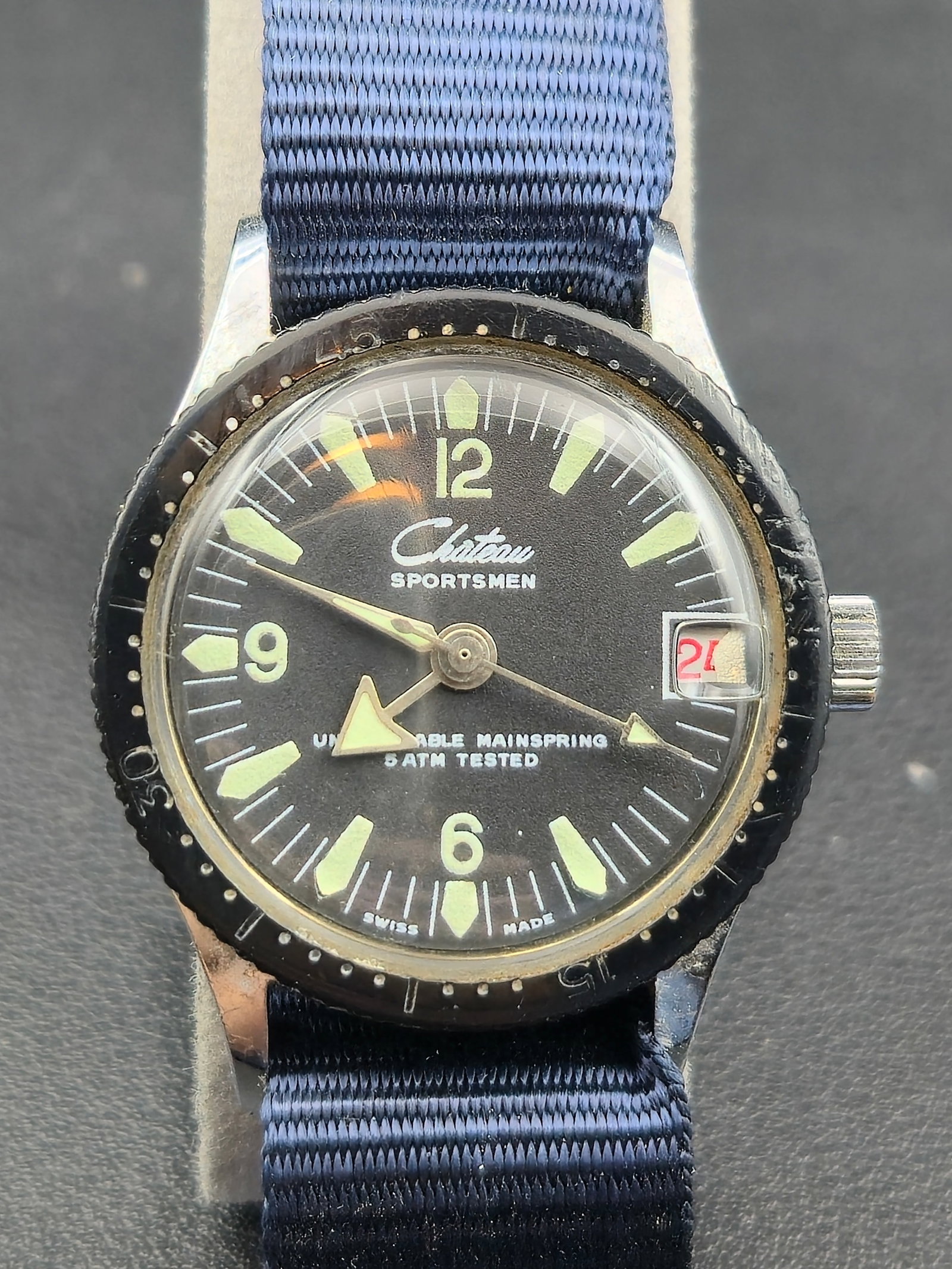 1960s Chateau “Sportsmen Mini Diver” Swiss Manual Wind 32mm Wristwatch (Running): Vintage Chateau Sportsmen Mini Diver wristwatch featuring a black dial with luminous triangle markers, date display at 3 o’clock, and a rotating diver-style bezel. Powered by a Swiss Wotania Ltd. 1-