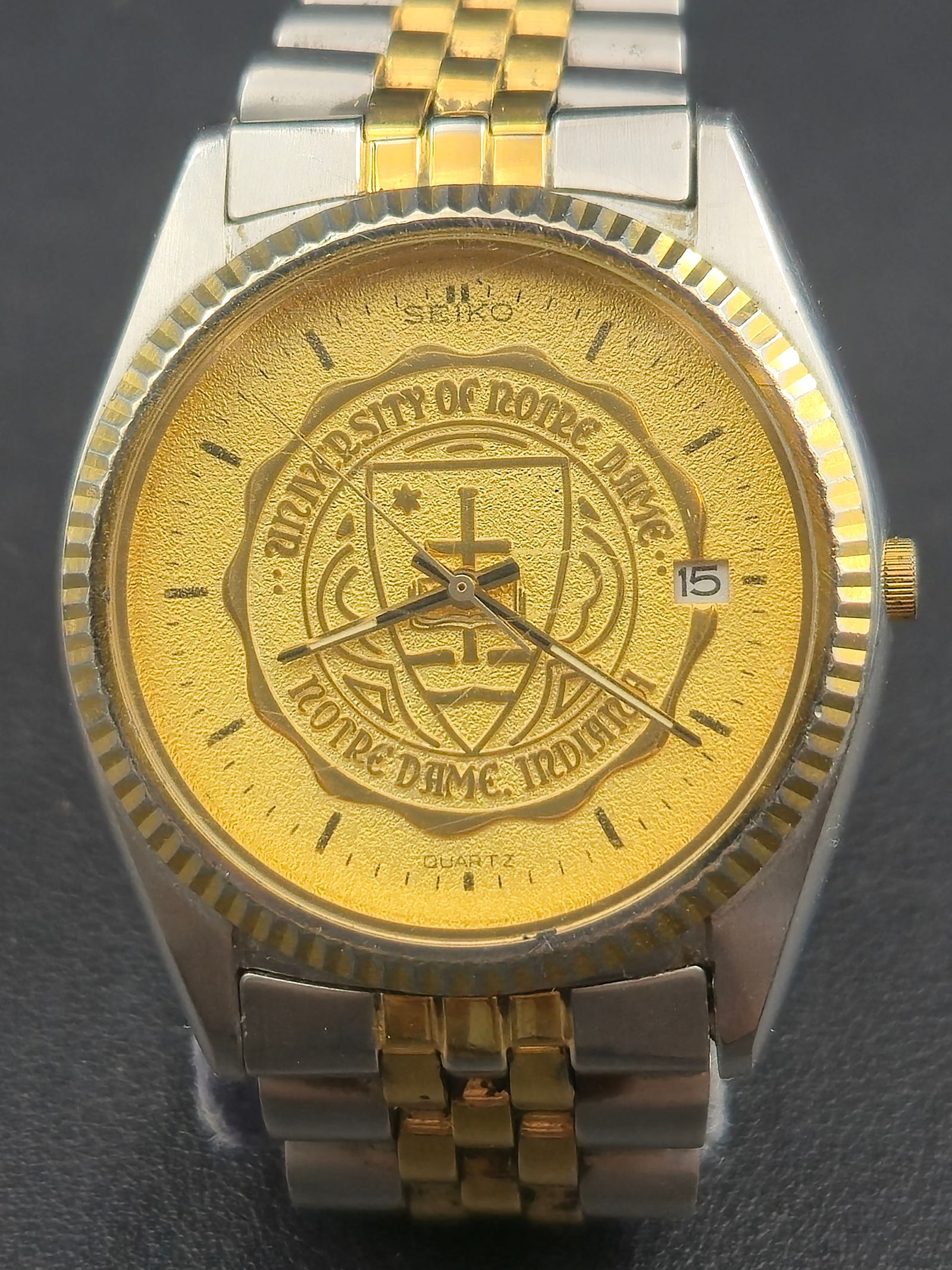 1980s Seiko “Notre Dame University” Quartz Two-Tone 35.6mm Wristwatch: Vintage Seiko Notre Dame University quartz wristwatch featuring the official University of Notre Dame, Indiana seal engraved across the gold-textured dial. The design combines Seiko’s precision quar