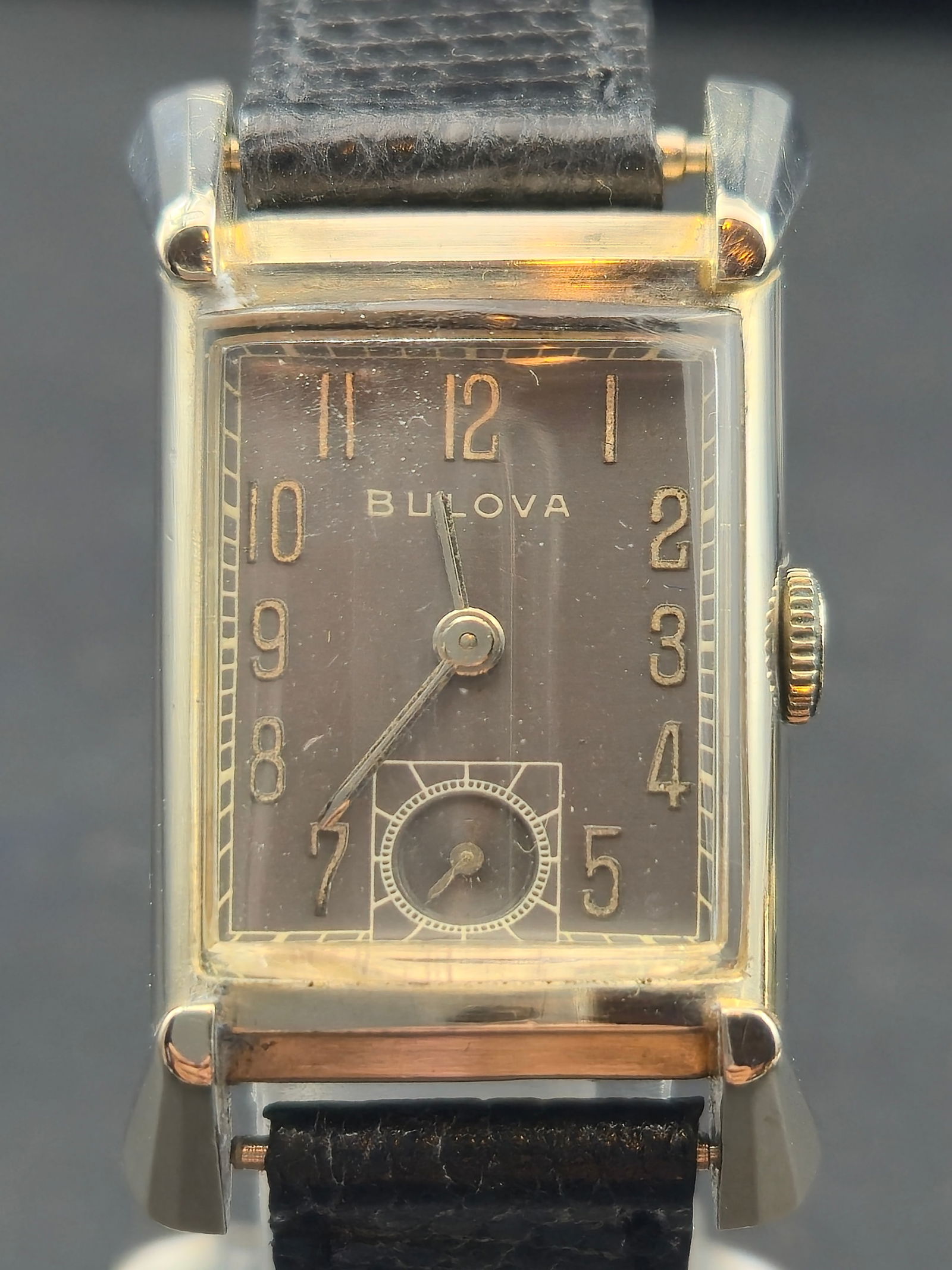 1947 Bulova 7AK 21J 10K White Gold-Filled Rectangular Tank Watch: Elegant late-1940s Bulova men’s wristwatch in a polished 10K white gold-filled rectangular case with stepped lugs and curved crystal. Features a silver-gray dial with gilt Arabic numerals and subsid