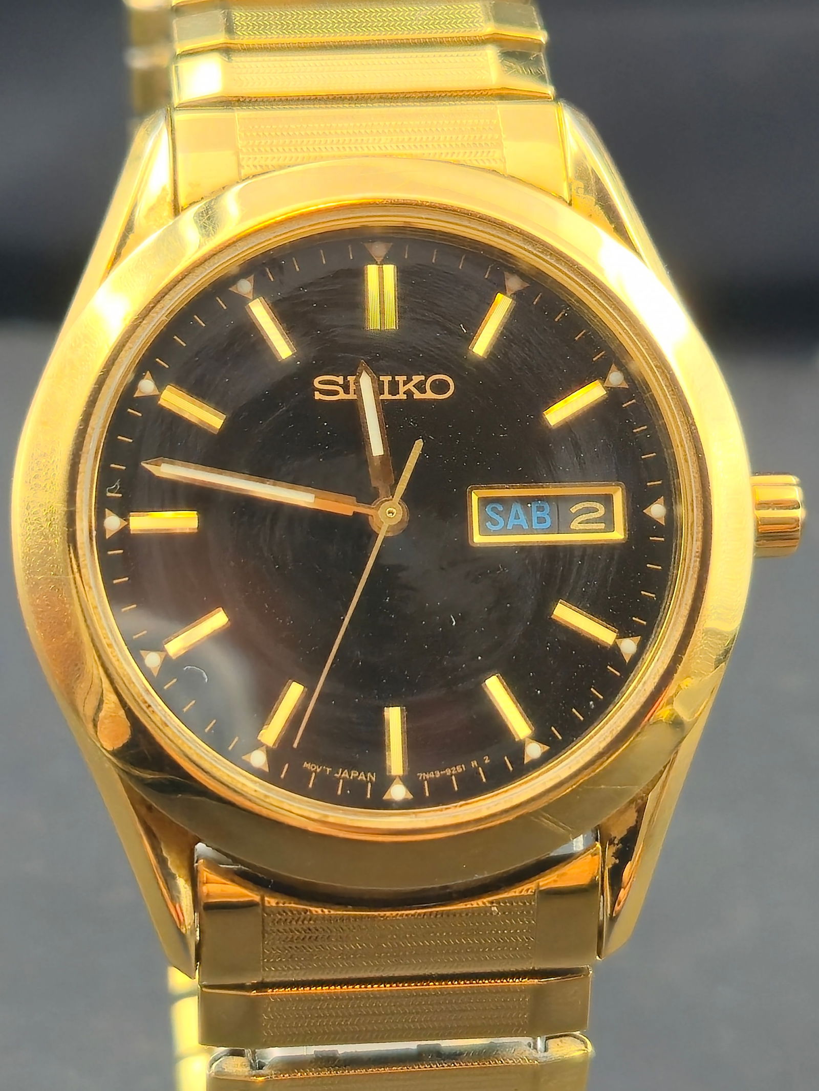 Seiko 7N43-9070 Gold-Tone Quartz Day-Date Wristwatch (37mm, Runs): Classic vintage Seiko quartz wristwatch featuring a rich black dial with gold-tone stick indices and a bilingual day-date display at 3 o’clock. The elegant gold-plated case is paired with its origin