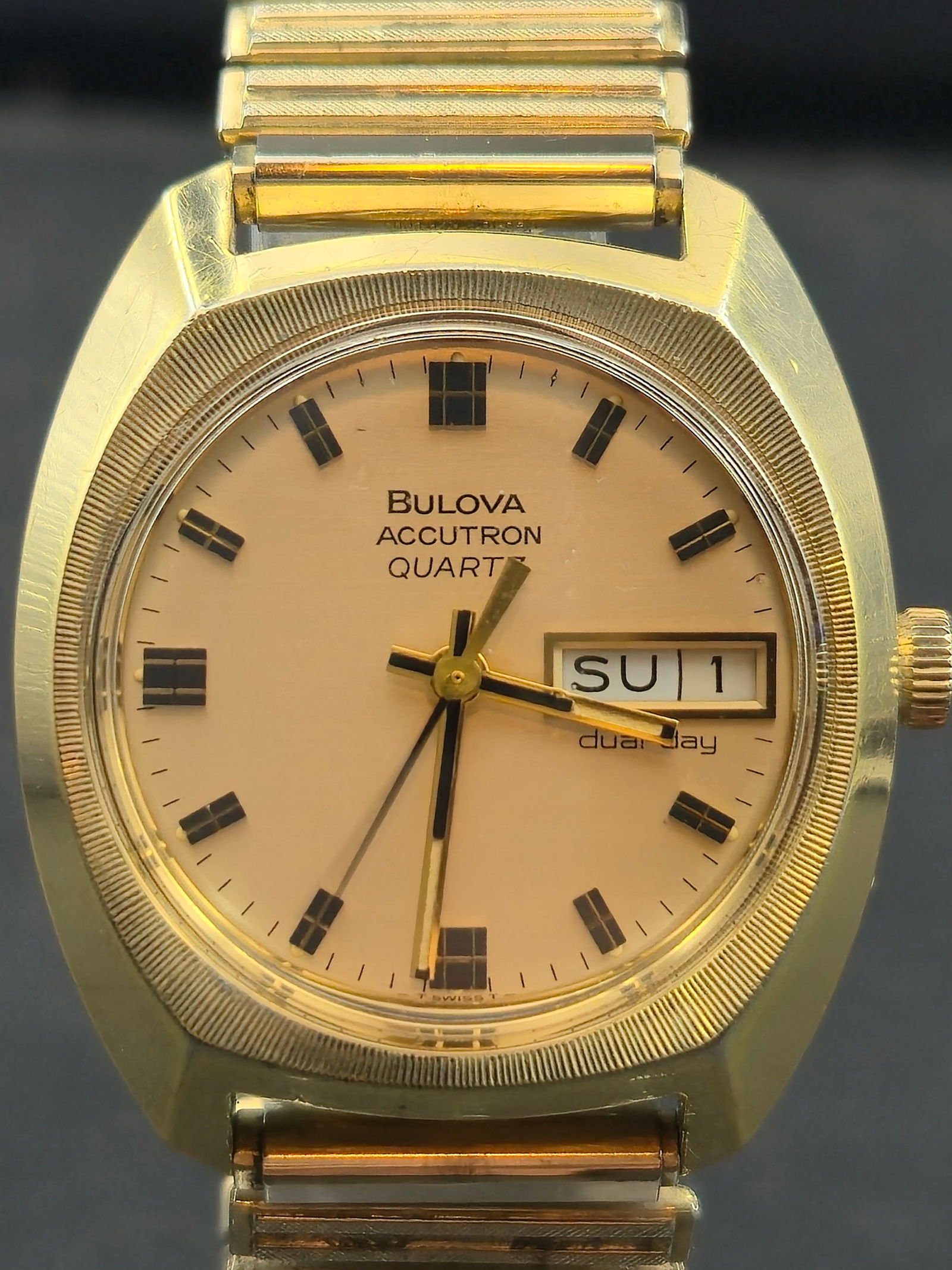 1977 Bulova Accutron Quartz “Pioneer LHE” 34mm Gold-Tone Dual Day-Date Watch (New Battery): Vintage Bulova Accutron Quartz “Pioneer LHE” wristwatch from 1977, featuring a distinctive gold-tone cushion case with vertically brushed bezel and champagne dial. This example was a corporate