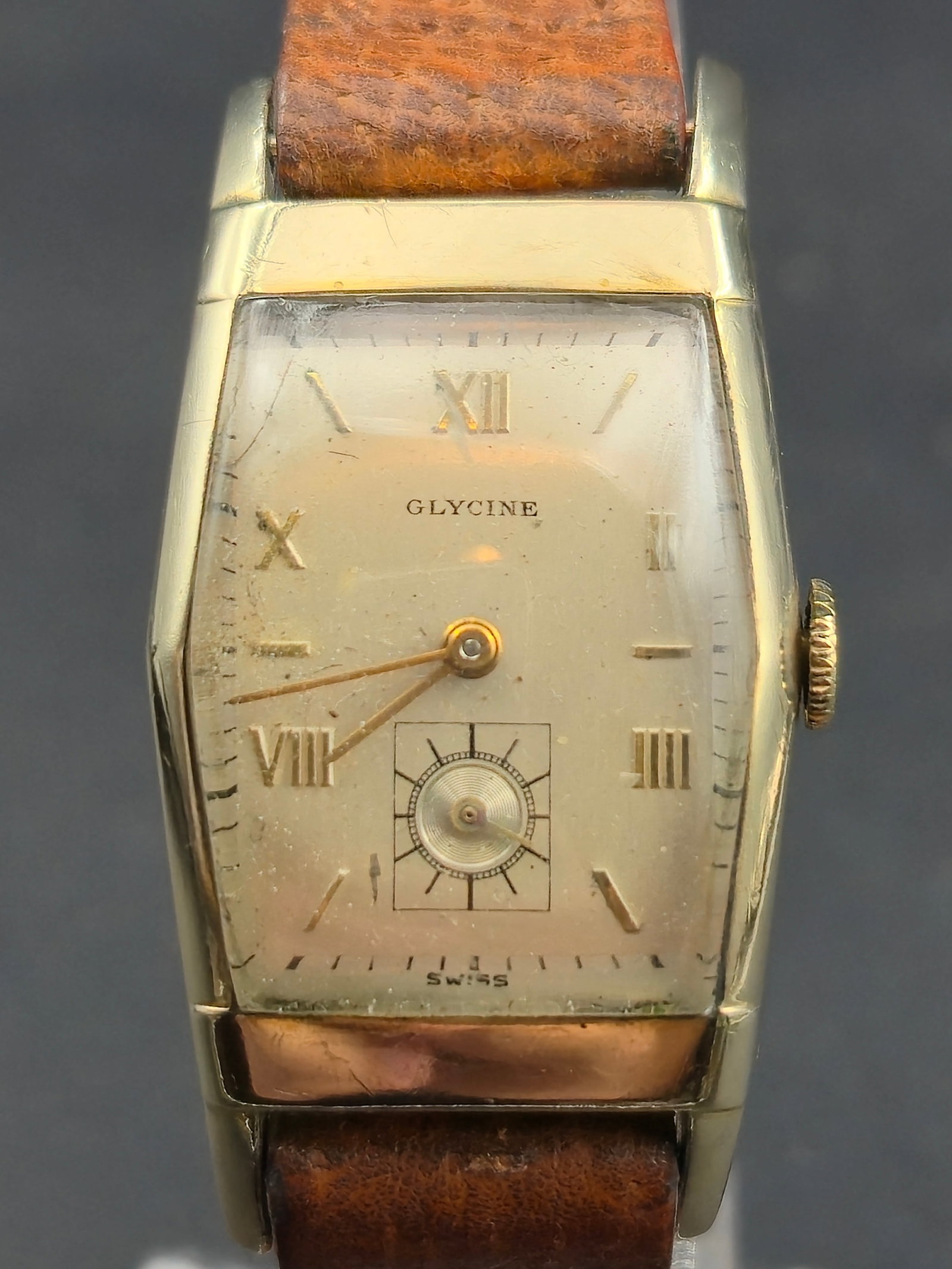 1947 Glycine Model 168 10K Rolled Gold Tank Wristwatch 17J Manual Wind – Runs: refined Glycine Model 168 wristwatch from 1947, housed in a 10K rolled gold plate Keystone Boulevard case with a distinctive curved rectangular “tank” design and domed crystal. The dial featur