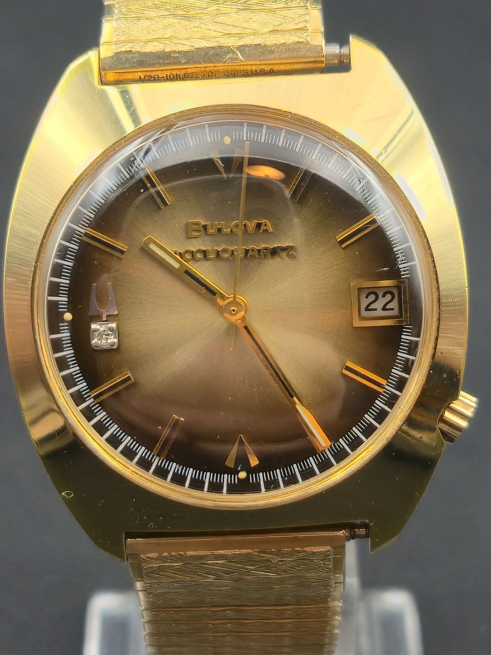 1973 Bulova Accuquartz 35mm 10K Gold Filled Diamond Dial Tuning Fork Watch: Circa 1973 Bulova Accuquartz men’s wristwatch featuring a gold sunburst dial with a genuine diamond marker at 9 o’clock, gold-tone hour markers, baton hands, and date window at 3 o’clock. Powere