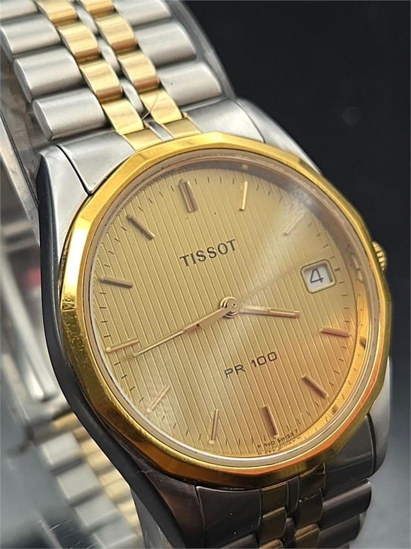 Tissot PR 100 Two-Tone Quartz Watch – 33.6mm: Classic Tissot PR 100 Swiss quartz wristwatch featuring a 33.62mm stainless steel case with gold-tone bezel and crown. Elegant brushed gold-tone dial with matching hands and indices, and a date window