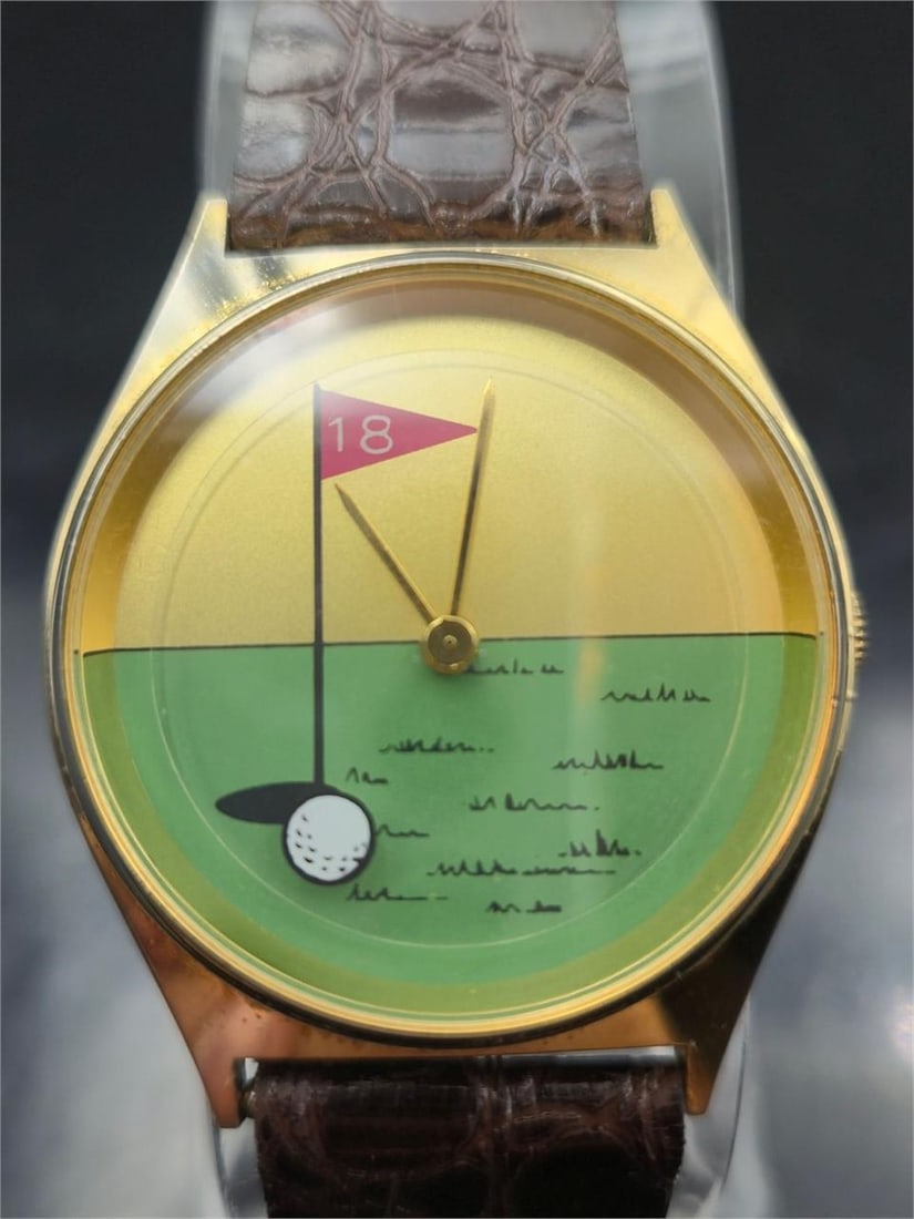 Golf Hole 18 Novelty Quartz Watch Running: Fun and colorful golf-themed quartz wristwatch featuring a whimsical dial with a putting green design, flag marked "18," and a golf ball at the hole. Gold-tone case with brown crocodile-pattern leathe