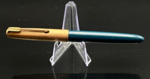 Vintage Parker 51 Fountain Pen – Teal Blue with Gold-Filled Cap: A fine example of the legendary Parker 51 fountain pen, featuring a dark teal blue barrel paired with a gold-filled cap. The cap is detailed with Parker’s iconic arrow clip and subtle engraved lines