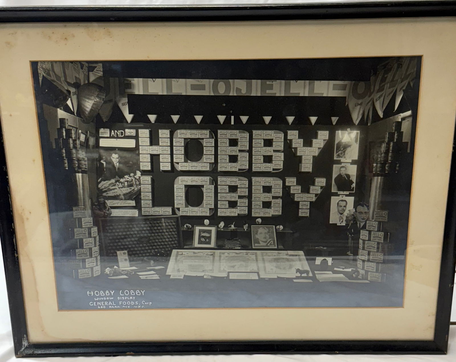 framed black-and-white photograph of a vintage "Hobby Lobby" window display General Foods Jello: framed black-and-white photograph of a vintage "Hobby Lobby" window display. The display features the words "HOBBY LOBBY" in large block letters.The text at the bottom of the image identifies it as a