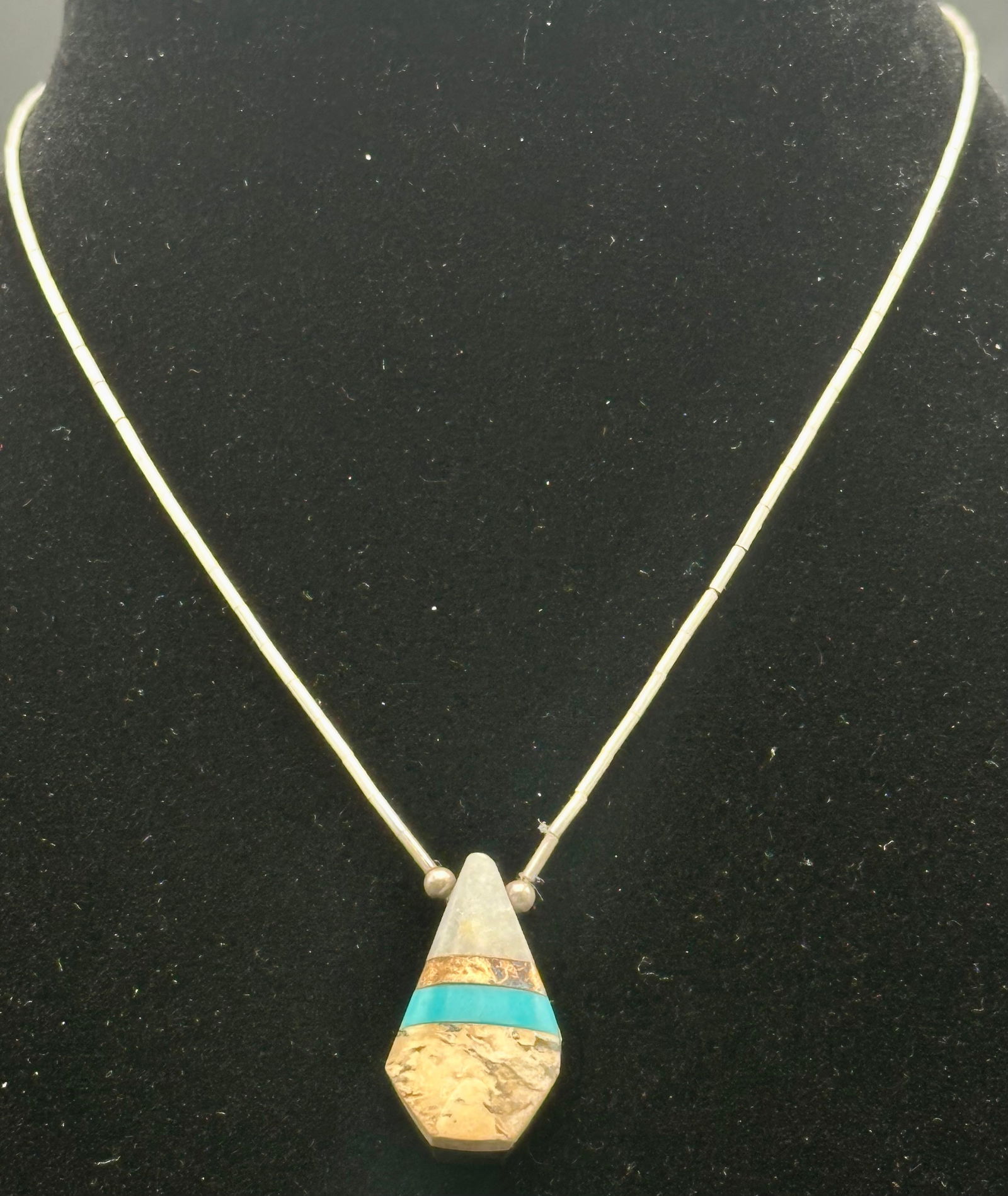 Vintage Sterling Silver Necklace with Inlaid Stone & Turquoise Accent – 9g: A beautiful vintage sterling silver necklace featuring a geometric pendant with inlaid turquoise, goldstone, and white stone layers. The pendant hangs from a tube-link silver chain with a barrel clasp