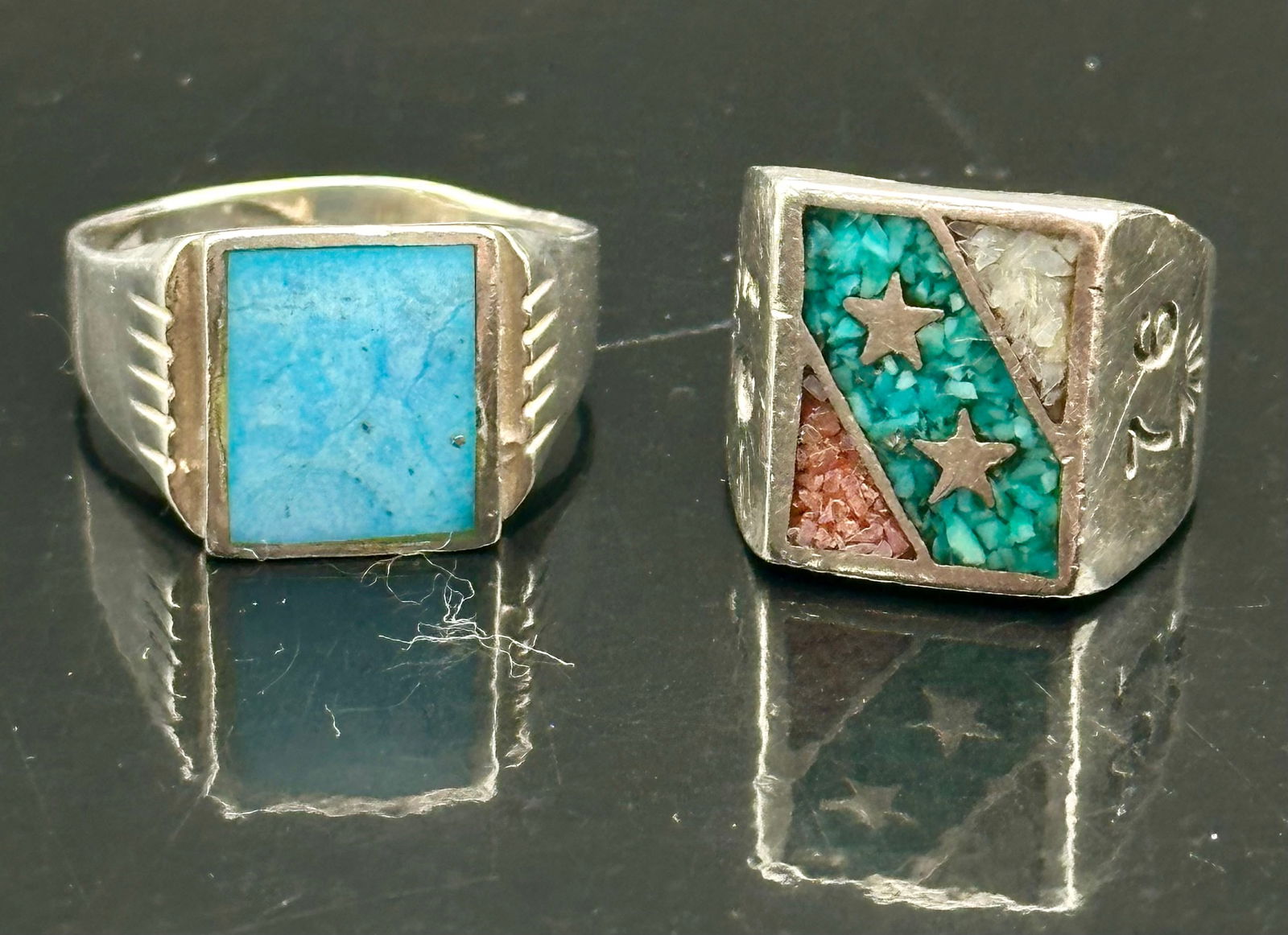 Lot of 2 Sterling Silver Turquoise & Inlay Men’s Rings – 20g: Pair of vintage sterling silver men’s rings featuring turquoise stone and inlay designs. One ring has a square turquoise cabochon, while the other showcases a colorful inlay pattern with a star moti