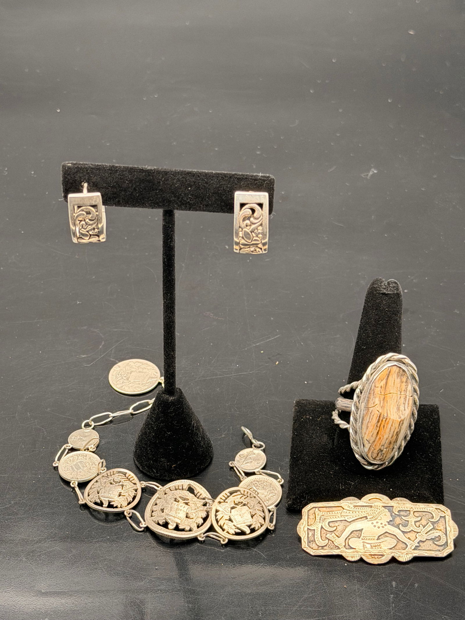 Vintage Mixed Silver Jewelry Lot – Rings, Bracelet & Brooch – 59g: Mixed vintage jewelry lot including carved hoop earrings, a cut-coin bracelet, a large natural stone ring, and an engraved figural brooch. Total weight 59 grams. Great set for collectors, resale, or c