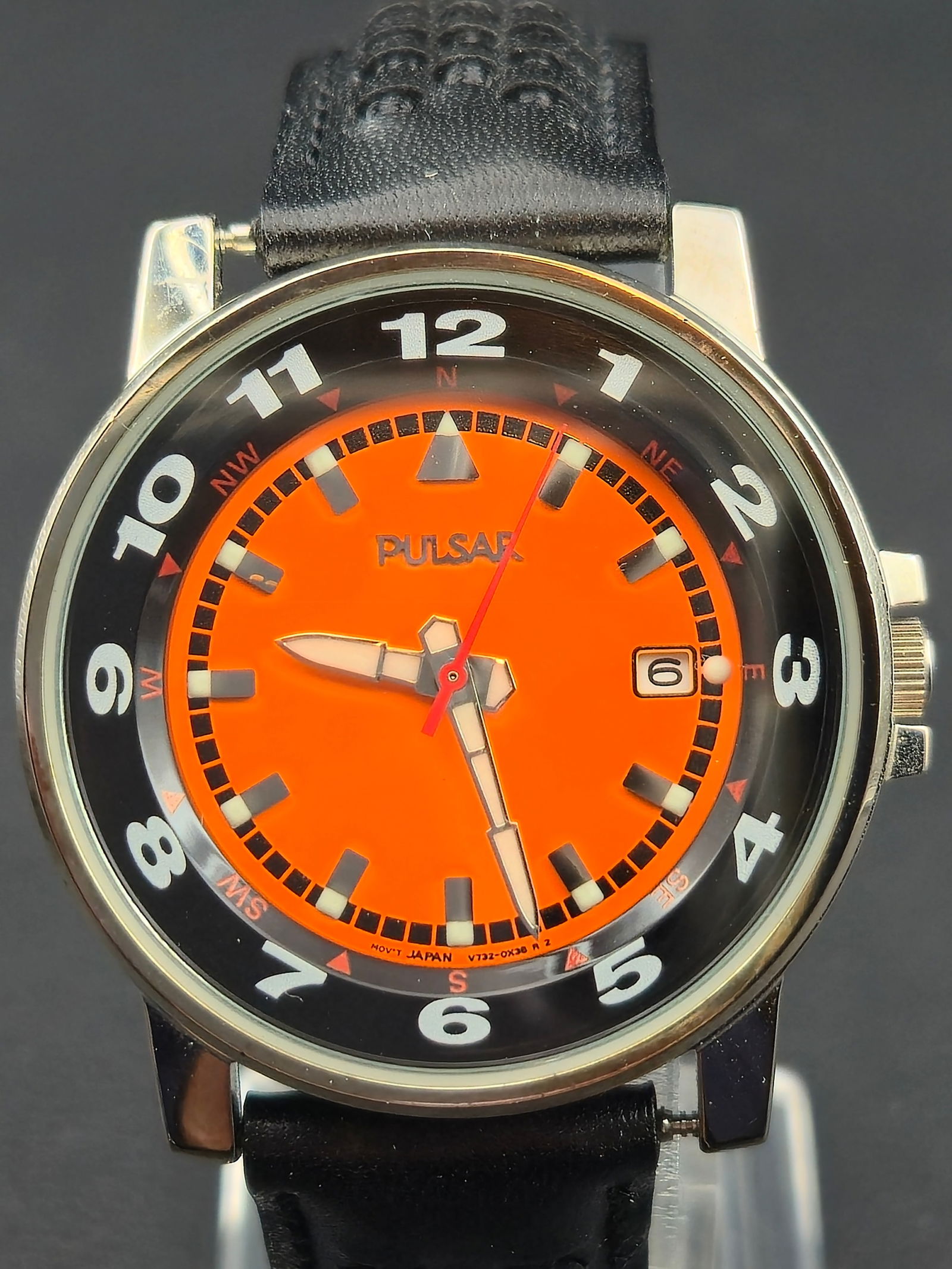 Pulsar V732-0K60 Quartz Orange Dial Stainless 38 mm – NOS: Vibrant Pulsar Quartz wristwatch, reference V732-0K60, featuring a striking orange dial with bold white Arabic numerals and a contrasting black outer chapter ring. Powered by a Japan-made Seiko Epson