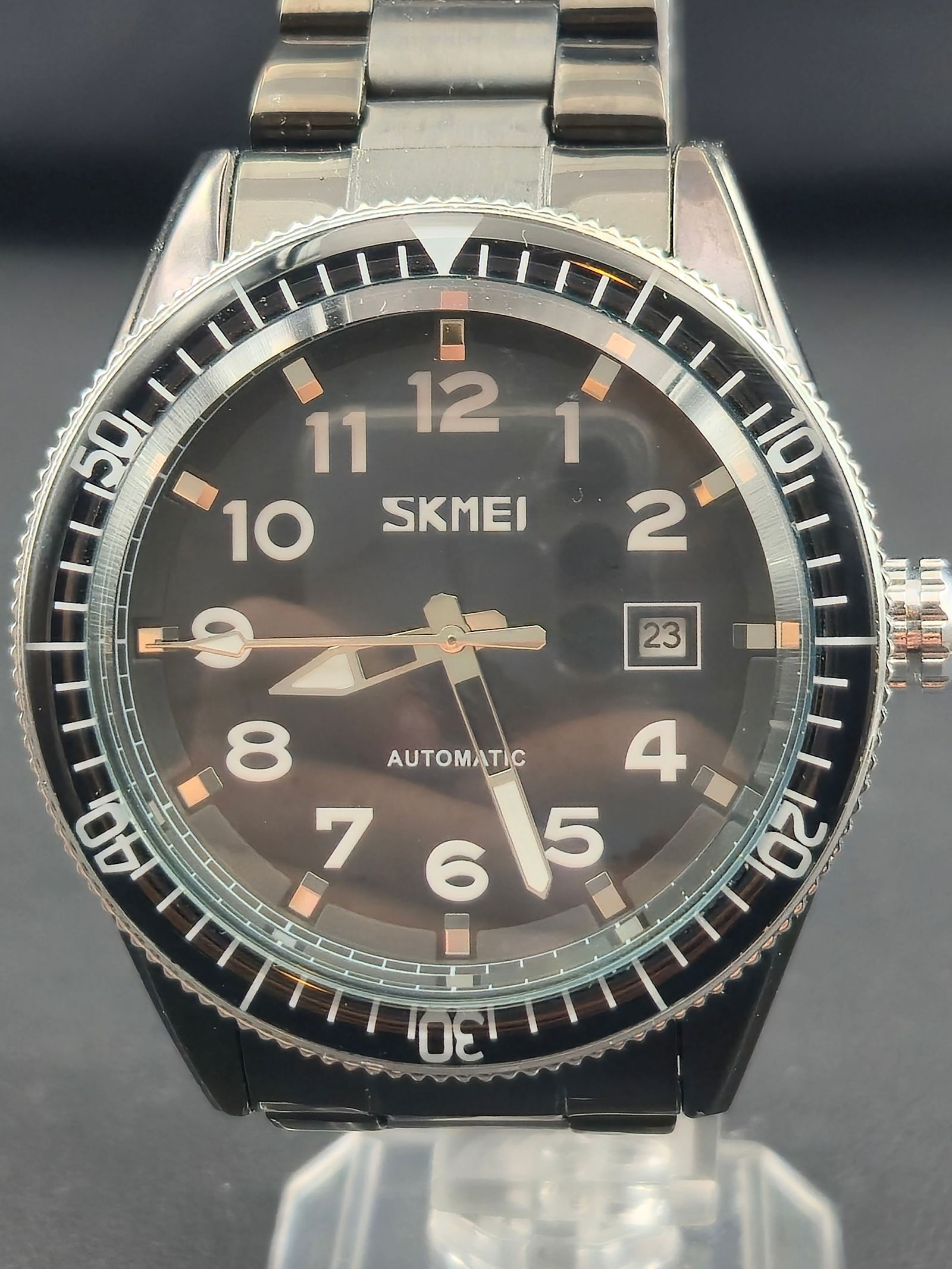 Modern SKMEI automatic wristwatch featuring a black stainless-steel case and matching bracelet. The: Modern SKMEI automatic wristwatch featuring a black stainless-steel case and matching bracelet. The watch measures 44 mm across and has a sporty diver-style aesthetic with a black dial, bold white num