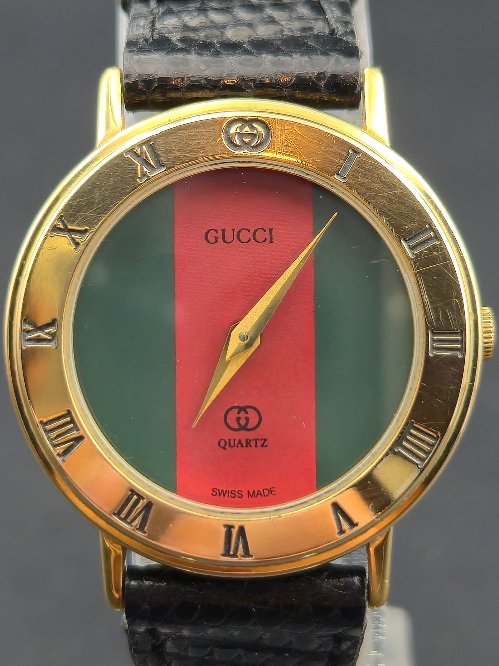 Gucci 3000L Swiss Quartz Gold-Plated 10 M Green-Red Dial 26mm – New Battery: This authentic Gucci 3000L Swiss-made wristwatch features the brand’s iconic green-red-green dial with gold hands and Roman numeral bezel. The 10 micron gold-plated case houses a six-jewel Gucci-sig