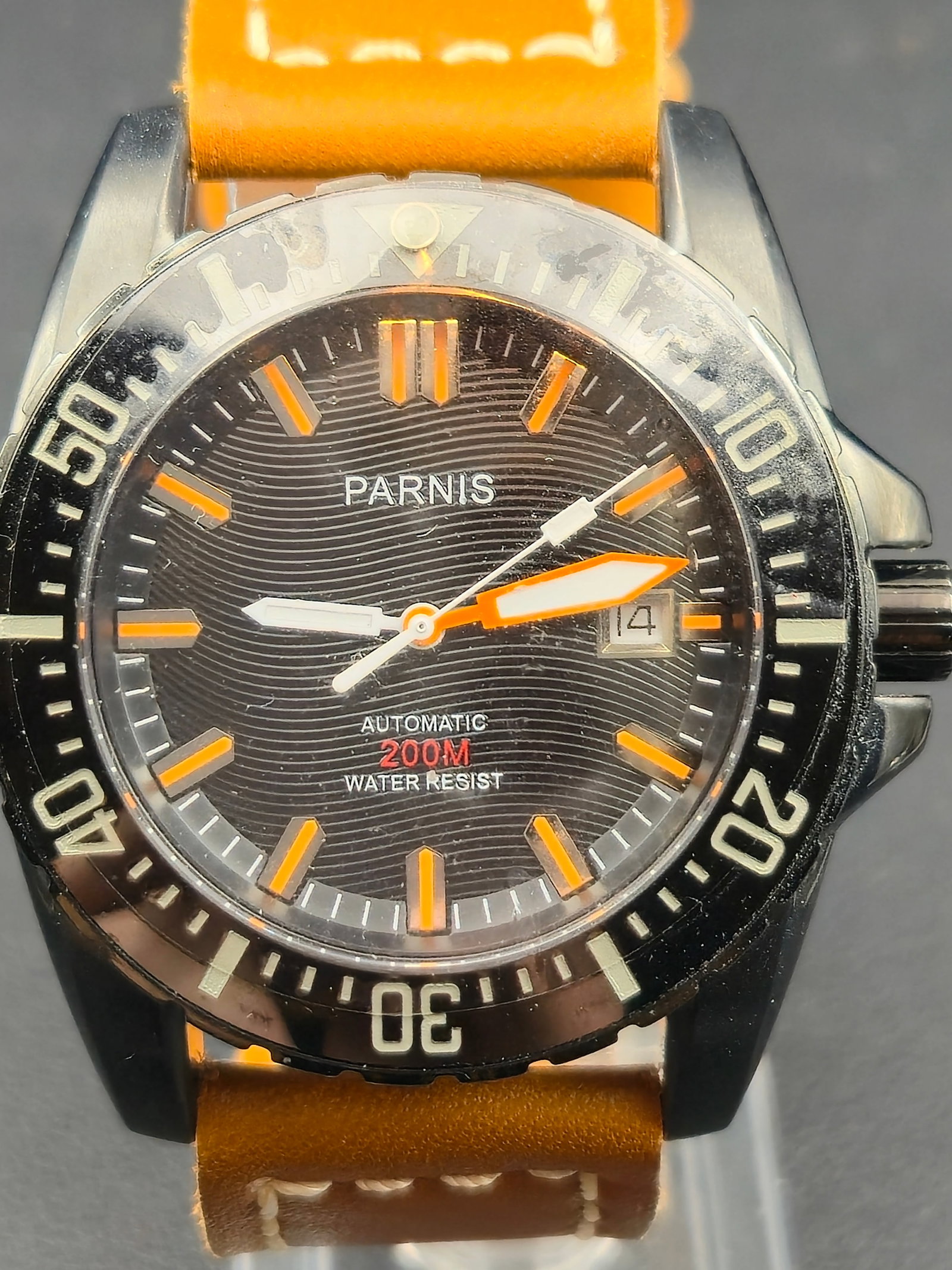 Parnis PA6007 Automatic Diver 46mm Black & Orange 200M NOS: New old stock (NOS) Parnis automatic diver’s watch featuring a black wave-textured dial accented with orange luminous hour markers and hands. The unidirectional black bezel and domed sapphire crysta