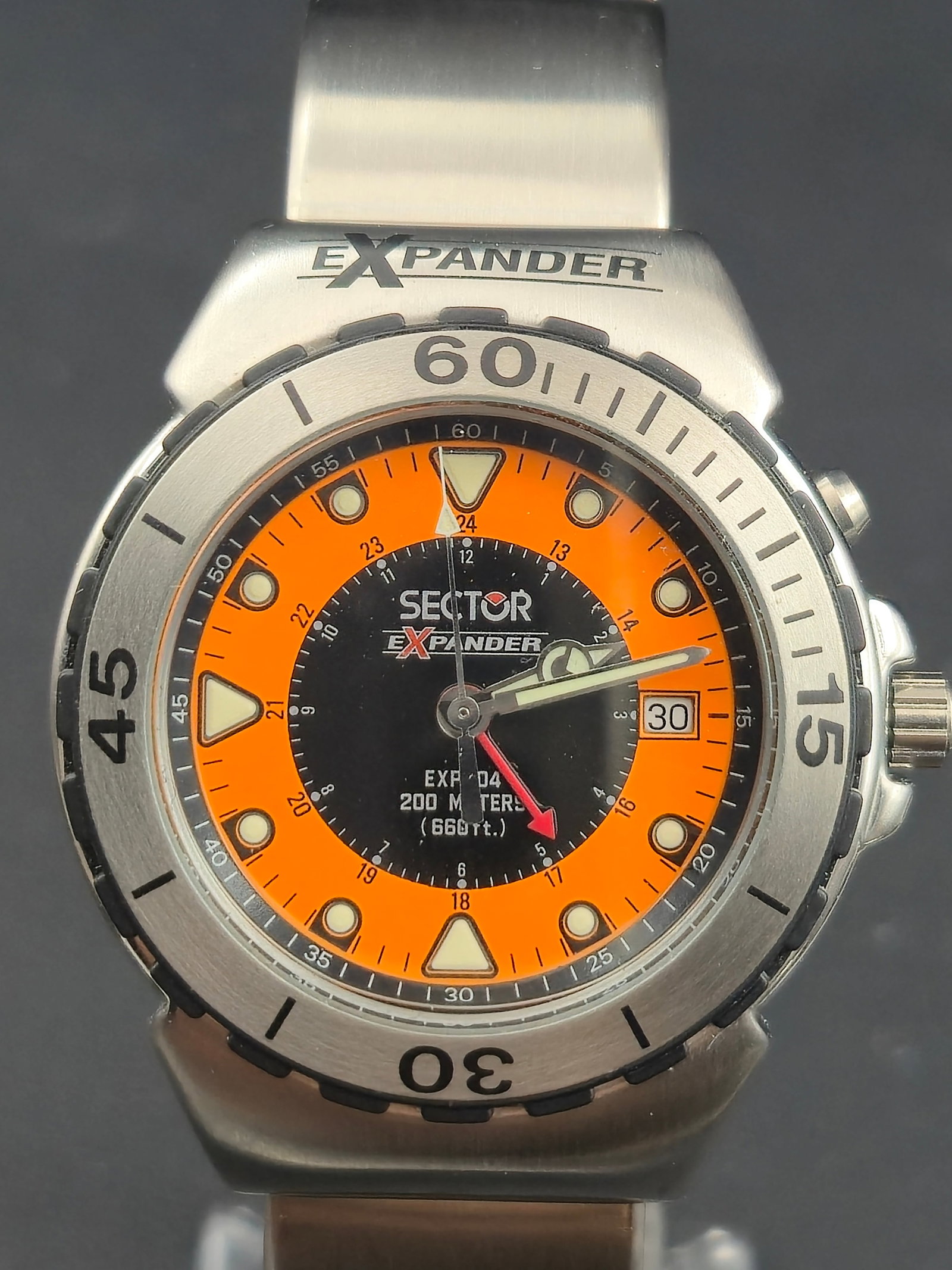 Sector Expander 404 Quartz Diver 38mm Orange Dial NOS Full Set: New-old-stock Sector Expander 404 men’s diver wristwatch featuring a striking orange and black dial with luminous indices, unidirectional rotating bezel, and stainless-steel bracelet. This quartz-po